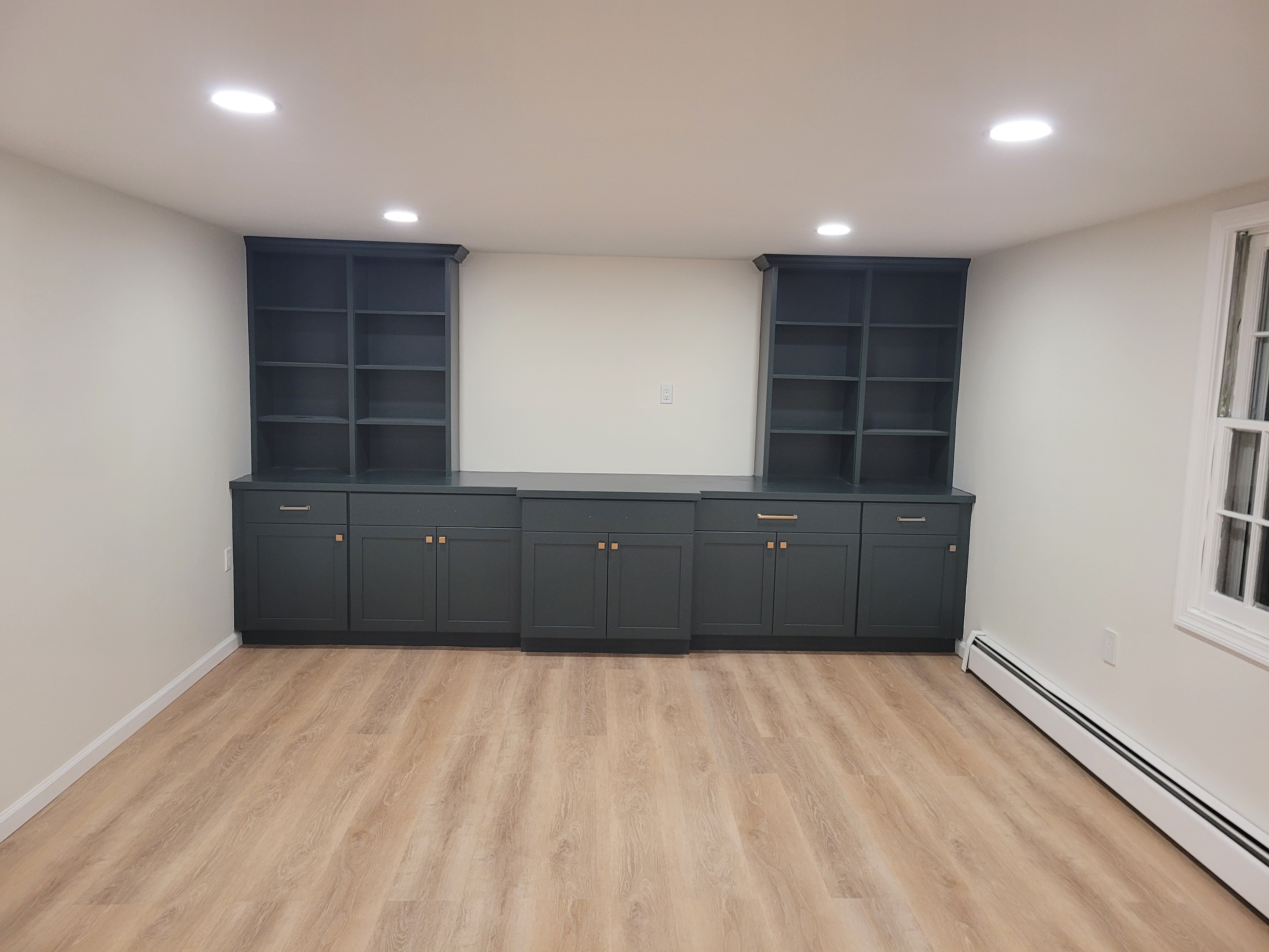 Finished basement with matching dark green built-in bookshelf and cabinet units by Rome Leite Home Improvement in Danbury, CT