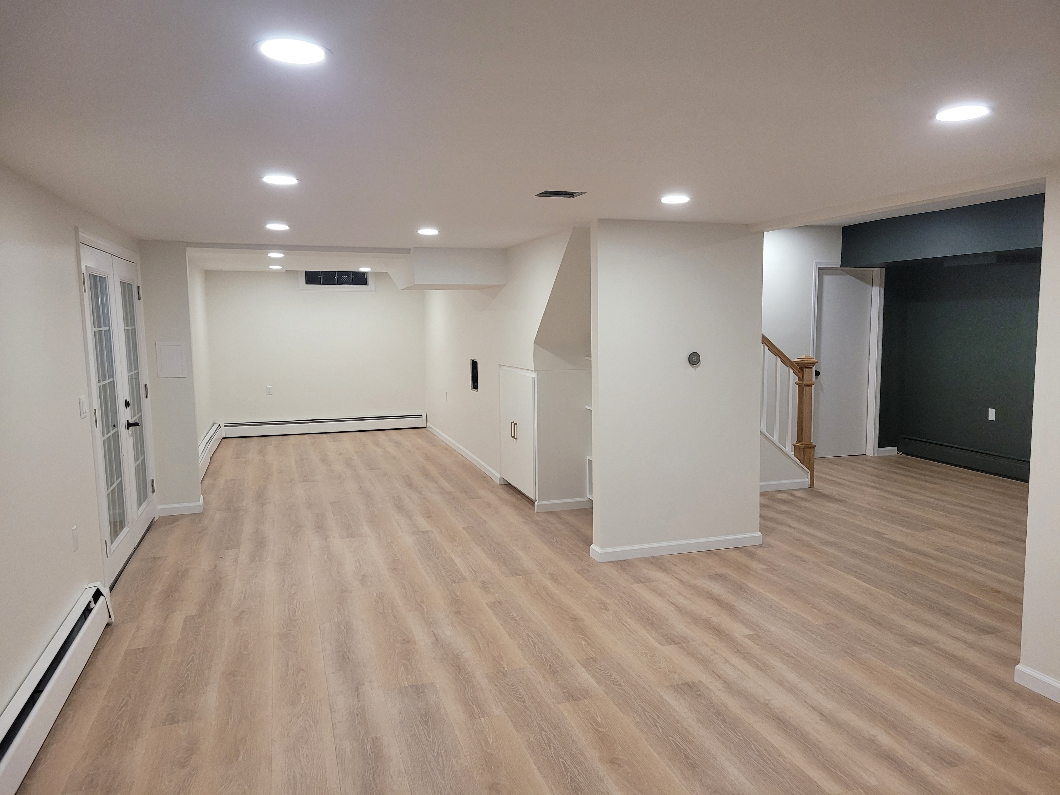 Finished basement showing the staircase, French doors, and dark accent wall by Rome Leite Home Improvement in Danbury, CT