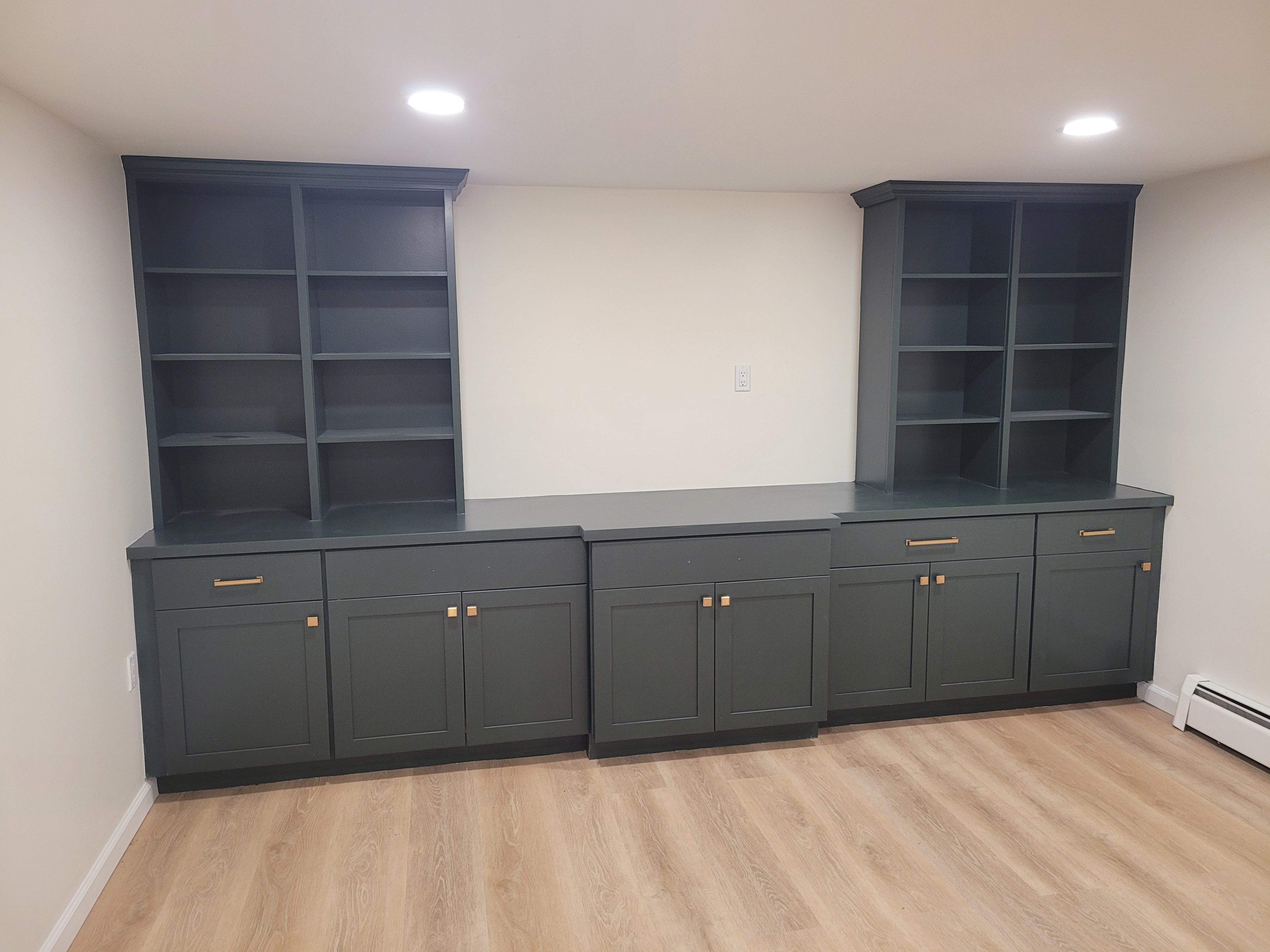 Finished basement with matching dark green built-in bookshelf and cabinet units by Rome Leite Home Improvement in Danbury, CT