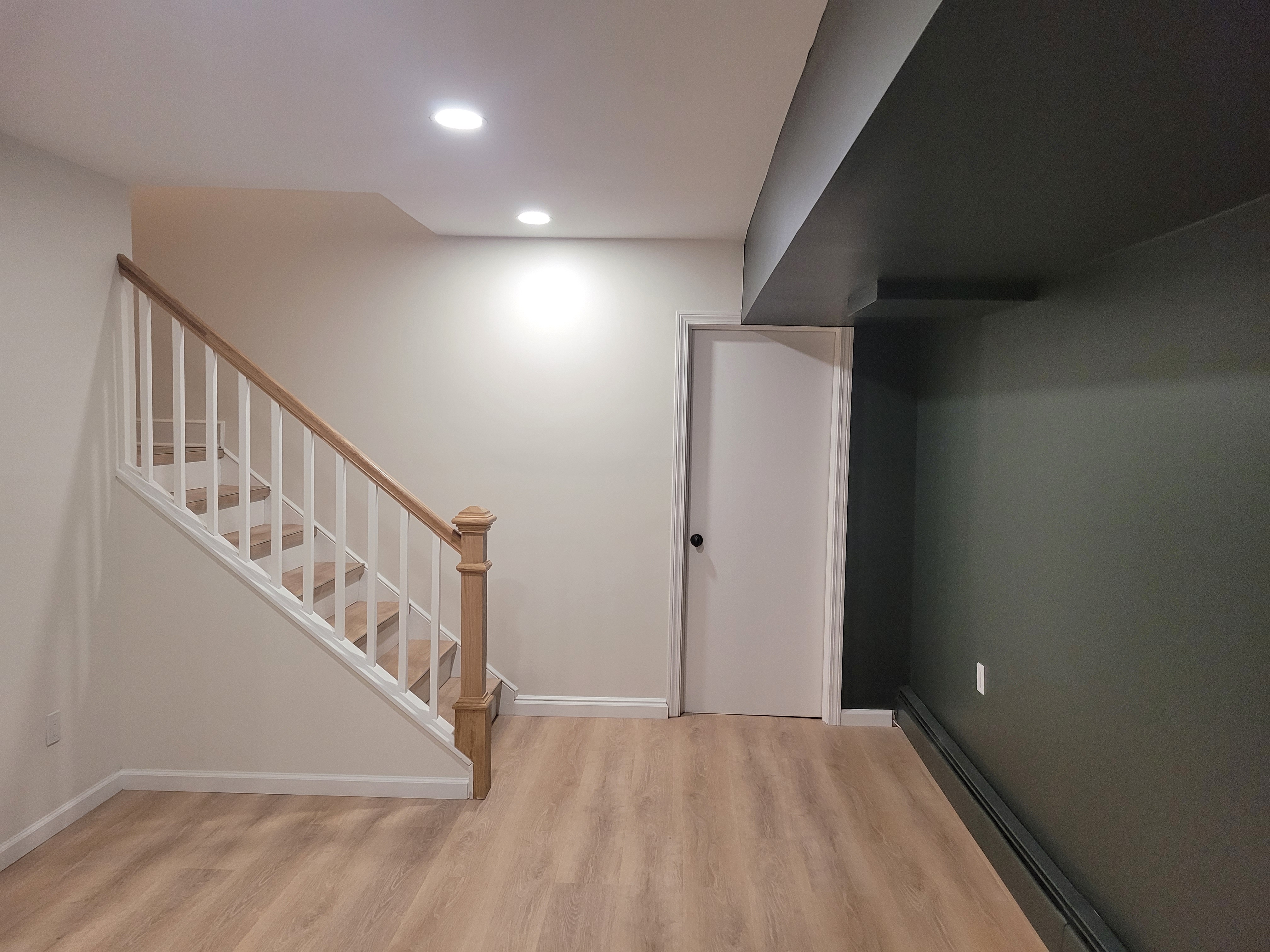 Finished basement staircase with white balusters and an oak handrail by Rome Leite Home Improvement in Danbury, CT
