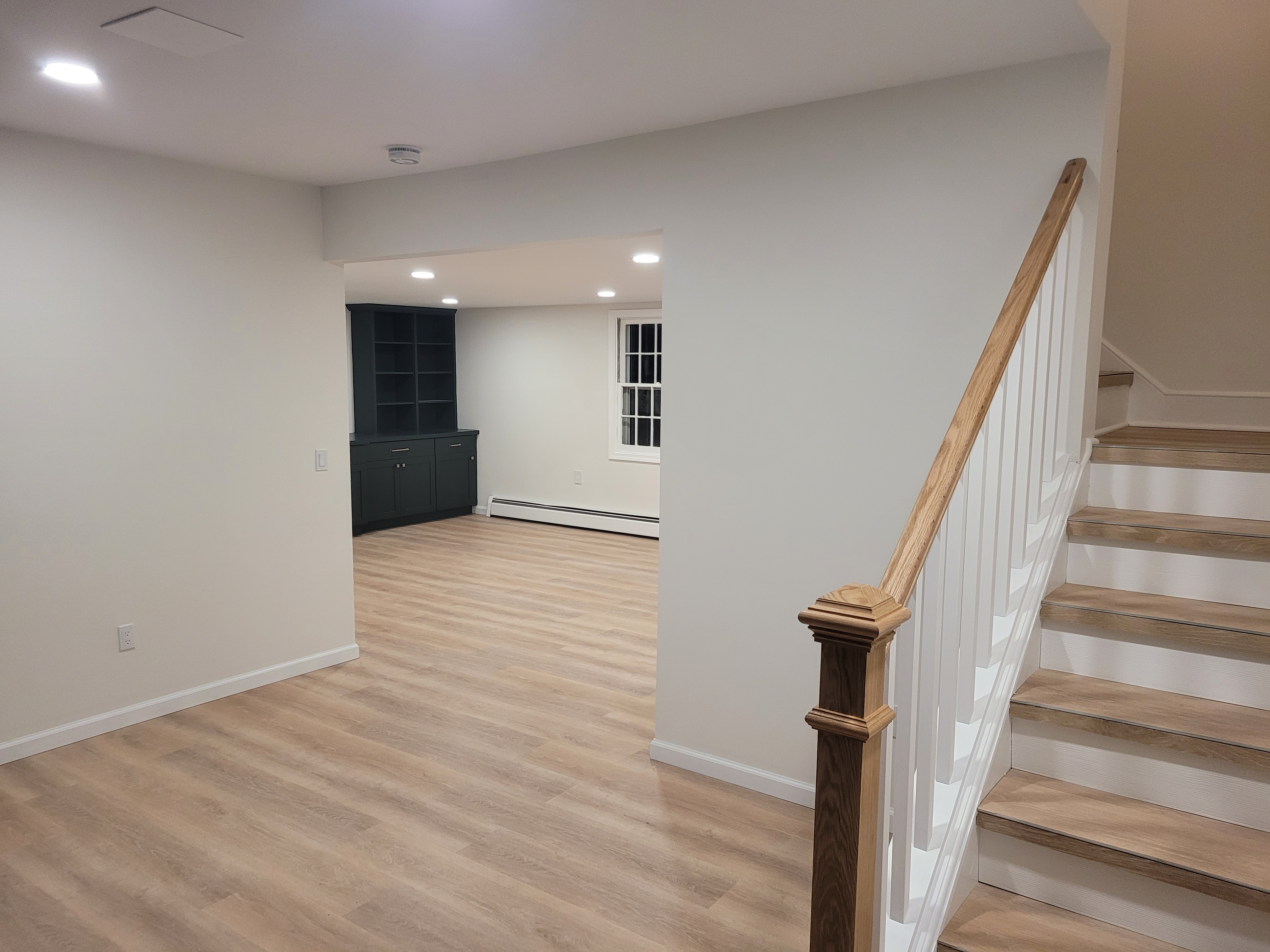 Finished basement corridor with the staircase and a dark built-in cabinet by Rome Leite Home Improvement in Danbury, CT