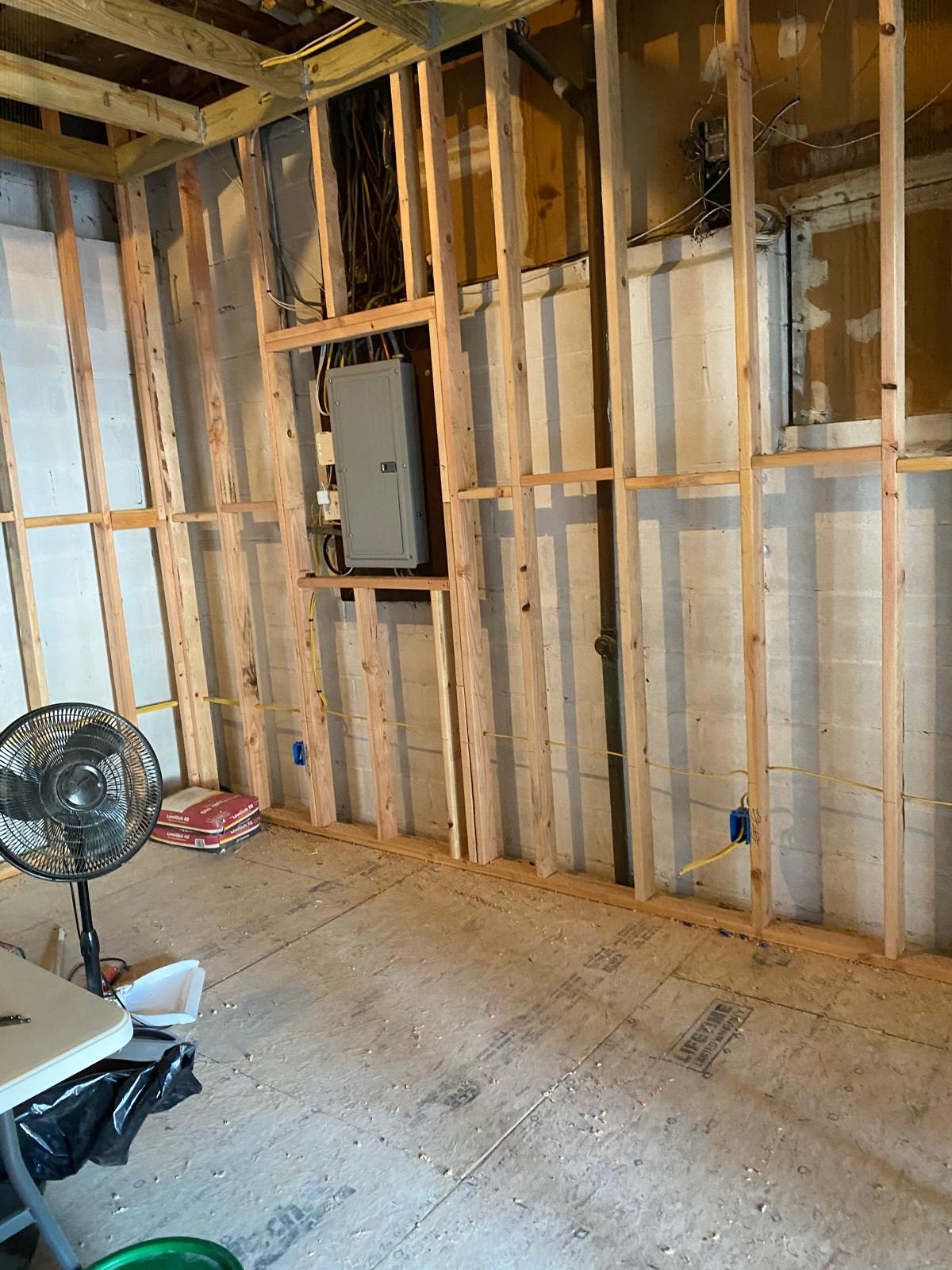 Basement wall framing with exposed studs, an electrical panel mounted mid-wall by Rome Leite Home Improvement in Danbury, CT