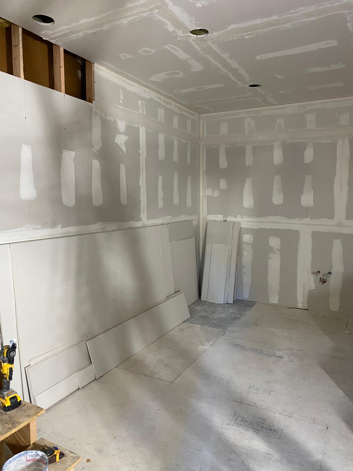 Taped and mudded drywall corner in a finished basement room with capped plumbing valves by Rome Leite Home Improvement in Danbury, CT