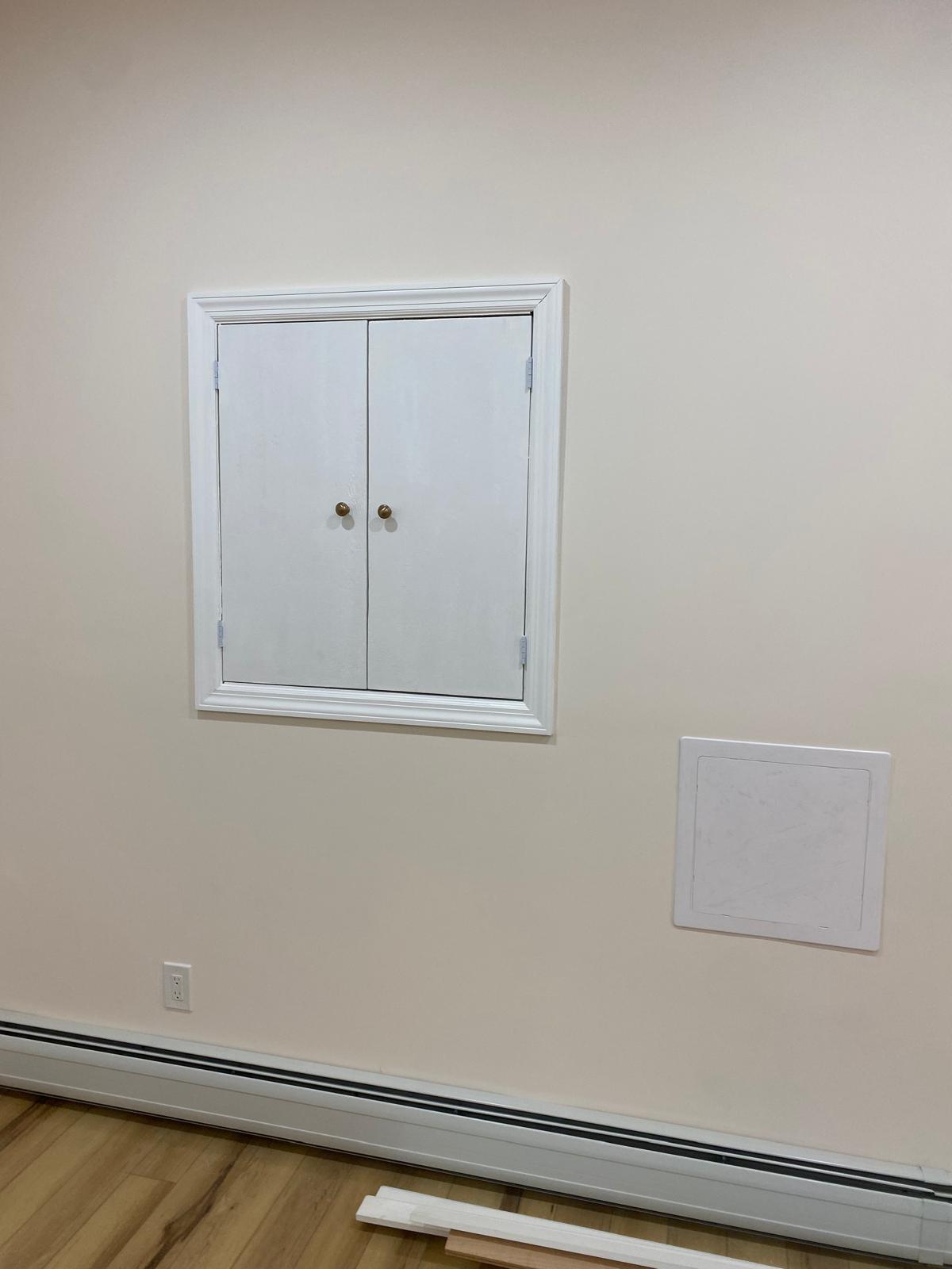 Two wall access panel doors in a basement next to an electrical outlet and baseboard heater by Rome Leite Home Improvement in Danbury, CT