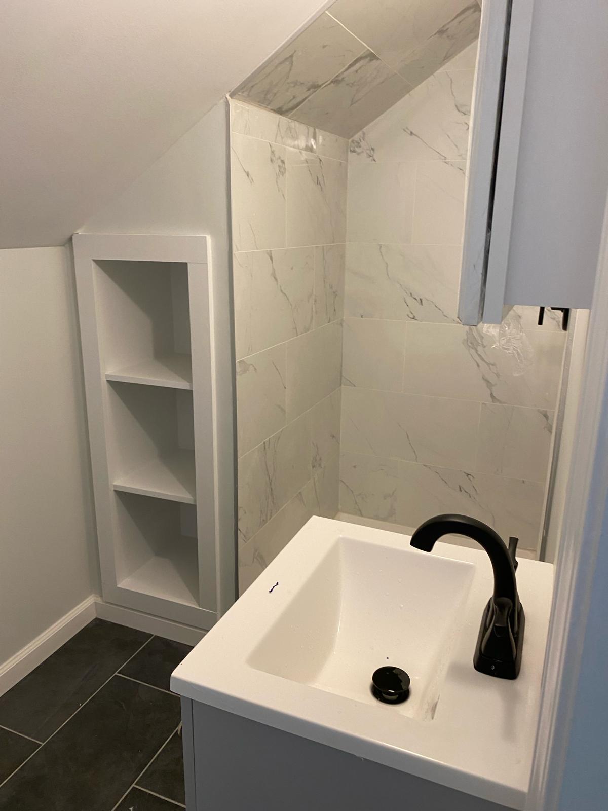 Finished bathroom with built-in shelving by Rome Leite Home Improvement