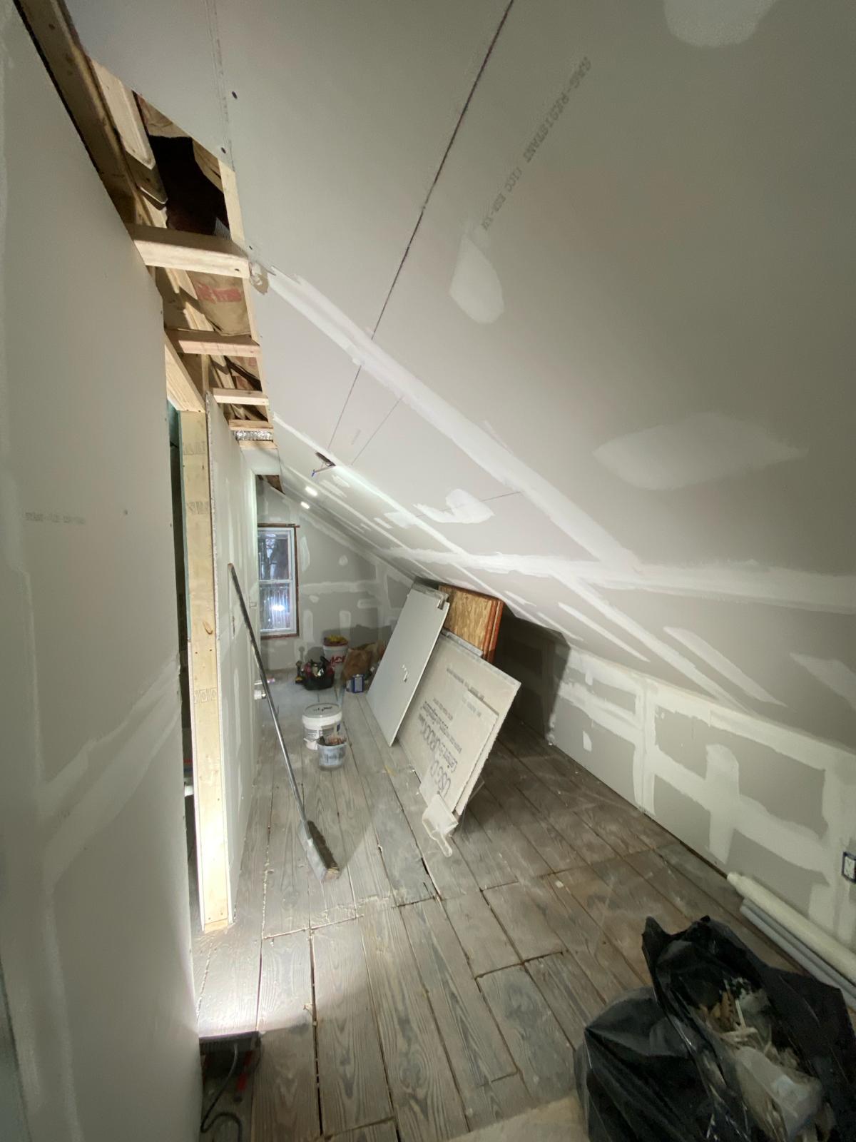 Attic room with drywalled sloped ceiling and an open stud wall by Rome Leite Home Improvement in Danbury, CT
