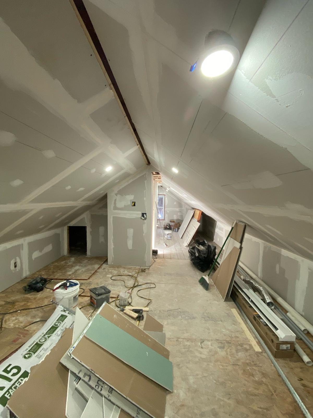 Attic room with drywalled vaulted ceiling, two windows, and insulation batts by Rome Leite Home Improvement in Danbury, CT