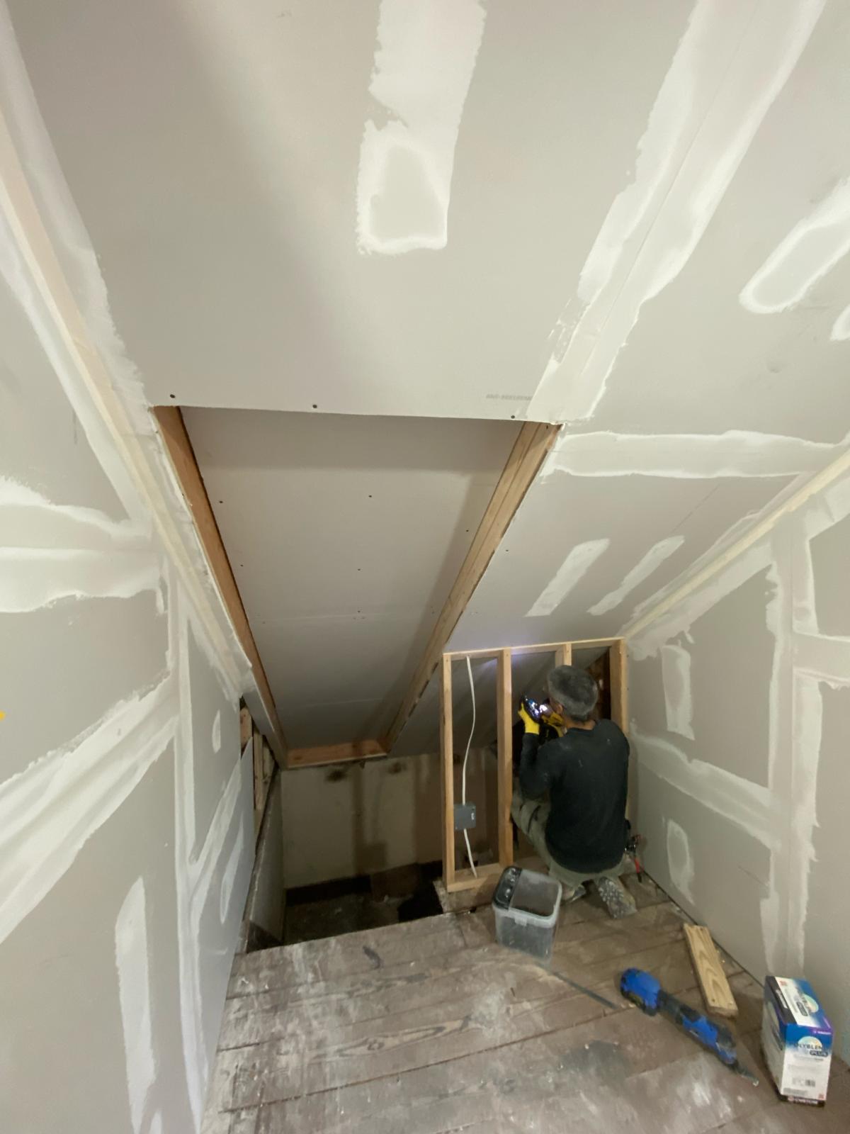 Worker installing an electrical outlet box in a framed attic stairwell by Rome Leite Home Improvement in Danbury, CT