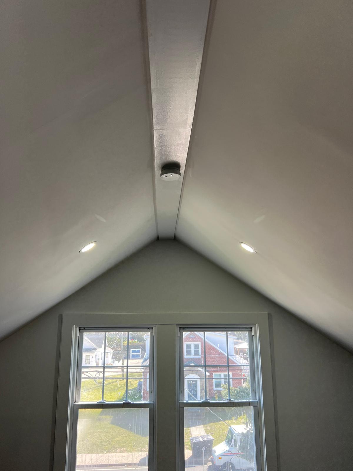 Small built-in attic access door set into a knee wall above dark hardwood flooring by Rome Leite Home Improvement in Danbury, CT