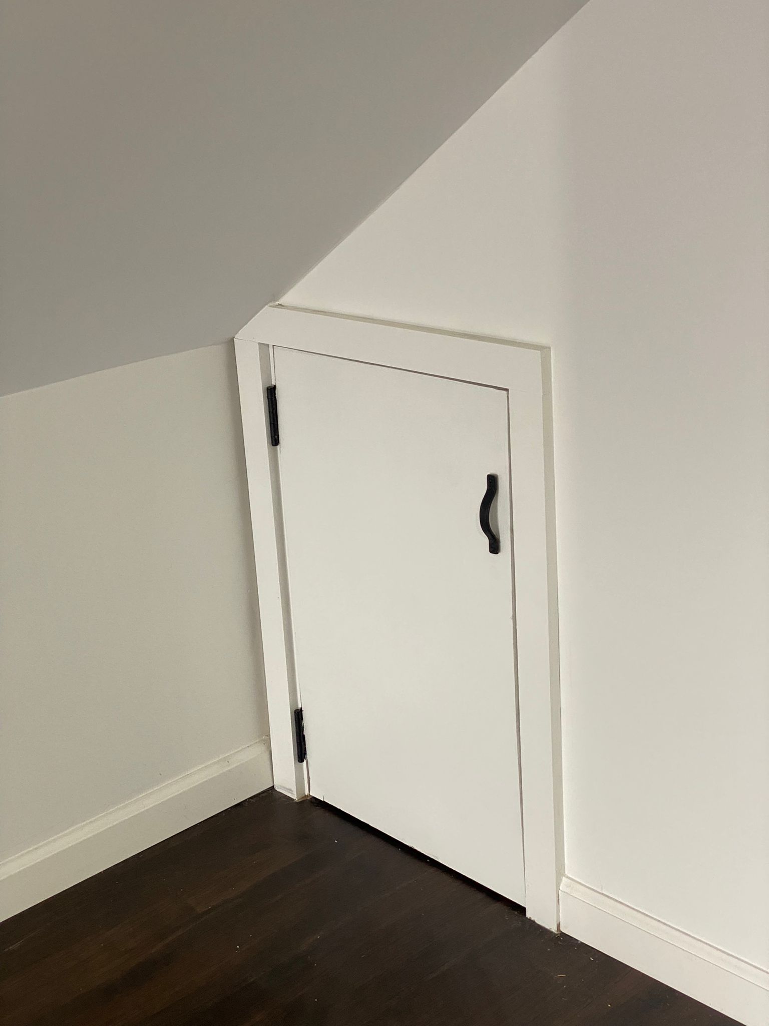Finished attic hallway with dark hardwood floors and a built-in cabinet under construction by Rome Leite Home Improvement in Danbury, CT