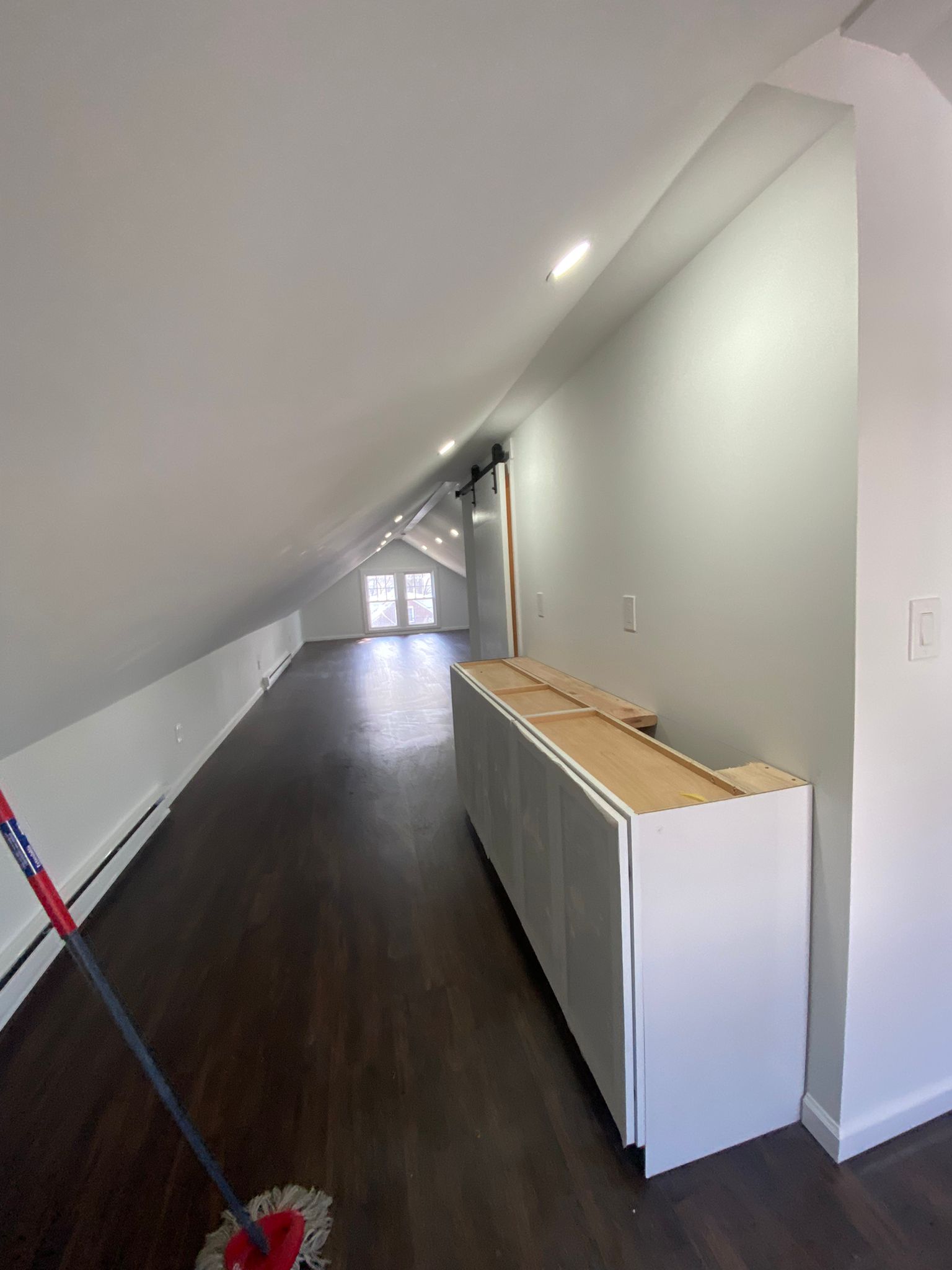 Transition between finished hardwood flooring and an unfinished attic storage area with exposed insulation by Rome Leite Home Improvement in Danbury, CT