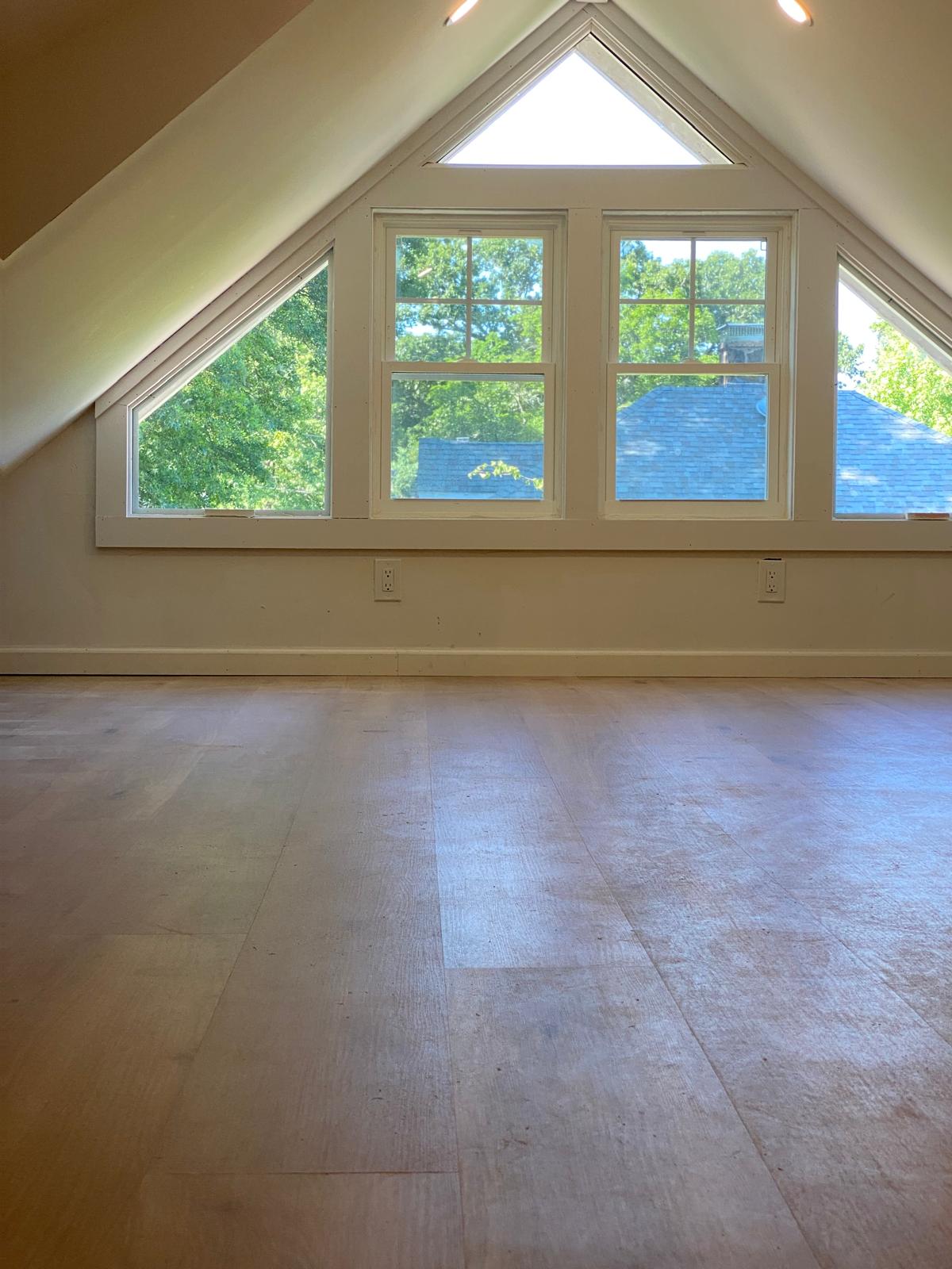 Finished attic room with vaulted ceiling, dormer window, and hardwood flooring by Rome Leite Home Improvement in Danbury, CT
