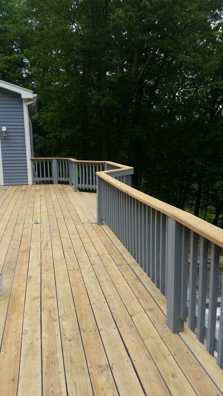 Newly built wood deck with painted railings and a curved corner by Rome Leite Home Improvement in Danbury, CT