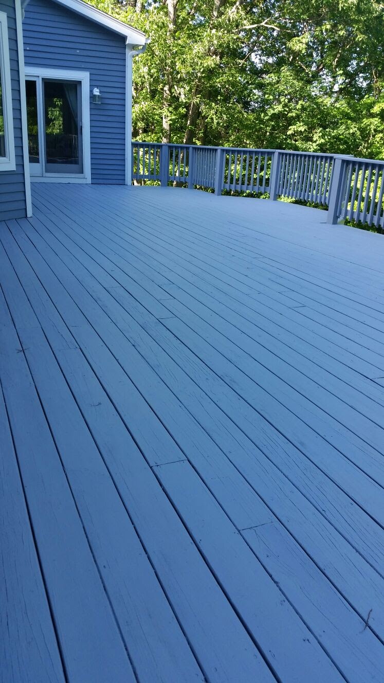 Wide wood deck attached to a house, with a sliding glass door and tree line beyond by Rome Leite Home Improvement in Danbury, CT