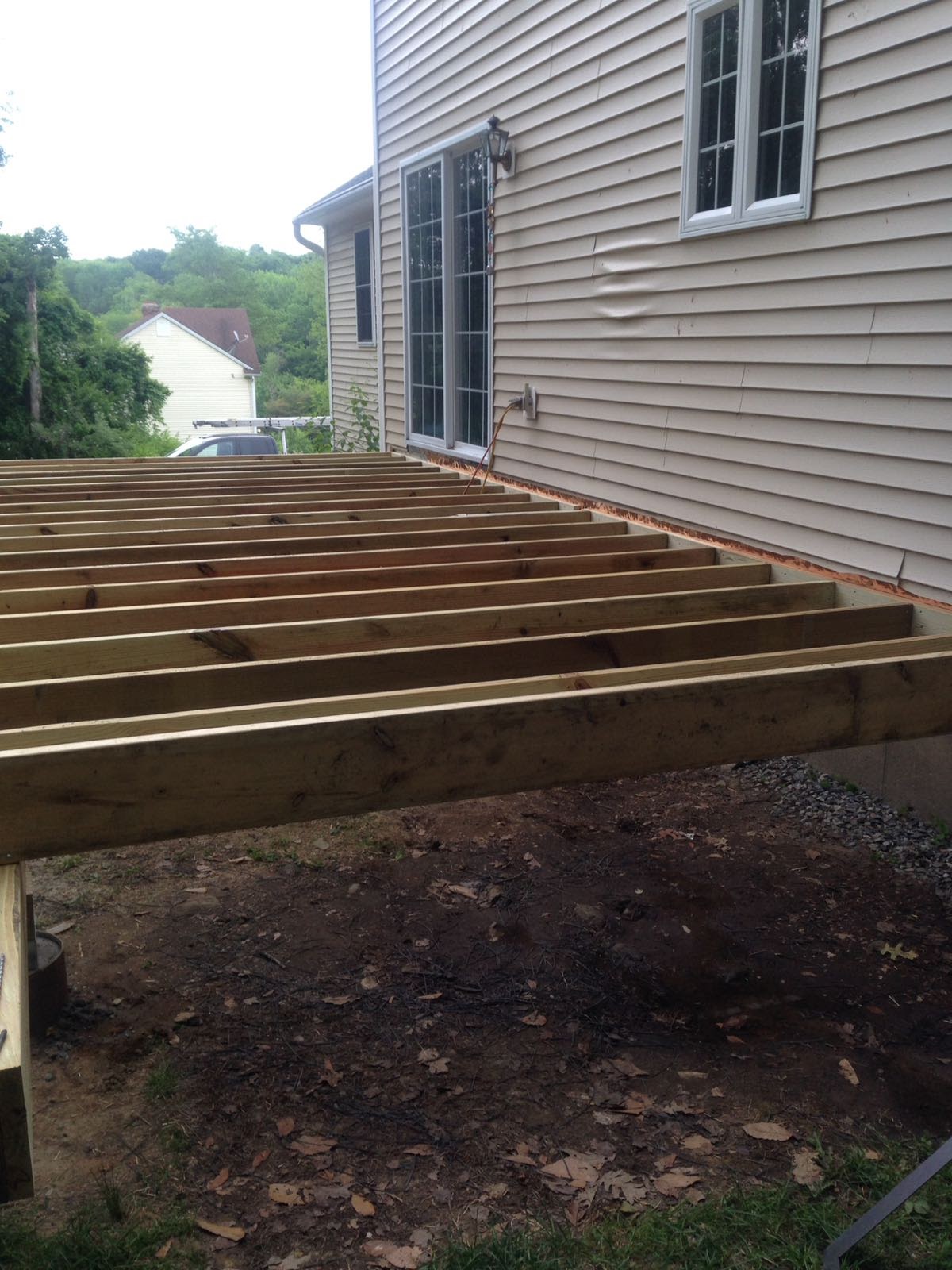 Newly framed deck floor joists extending from a house by Rome Leite Home Improvement in Danbury, CT