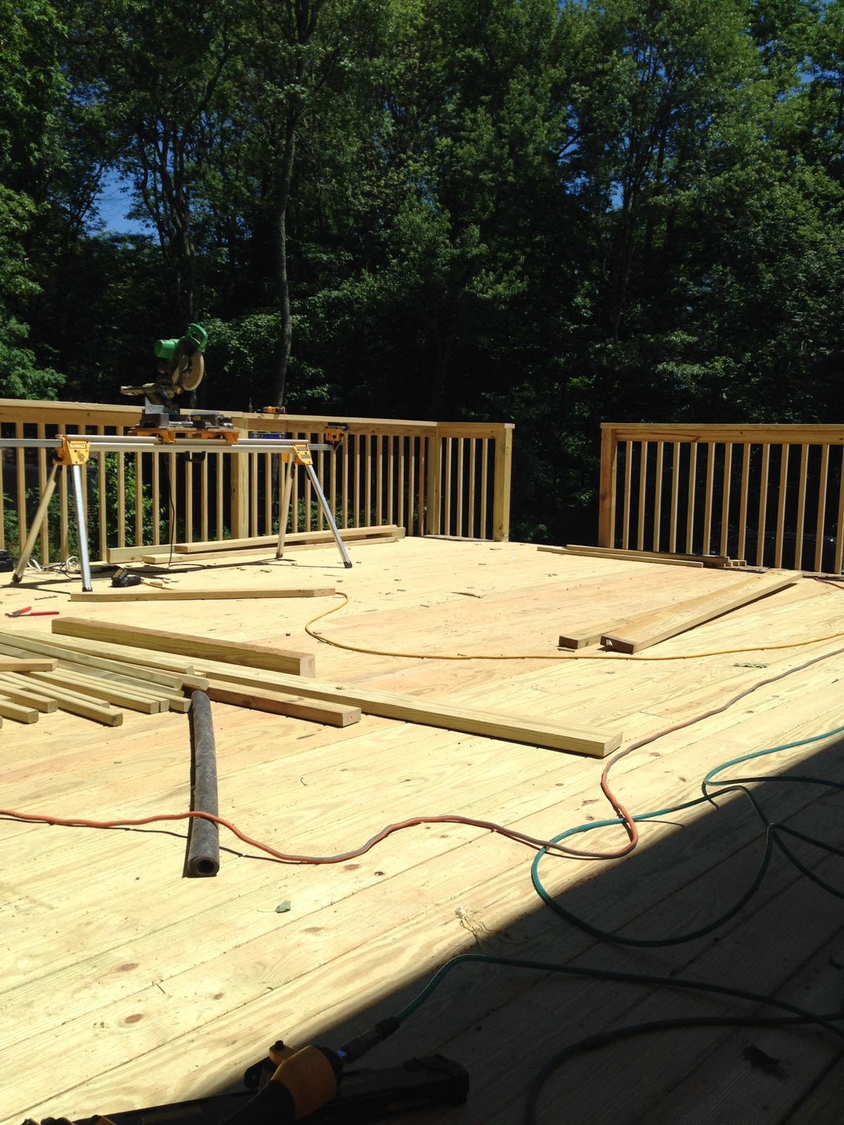 Deck subfloor under construction with a miter saw station and lumber by Rome Leite Home Improvement in Danbury, CT