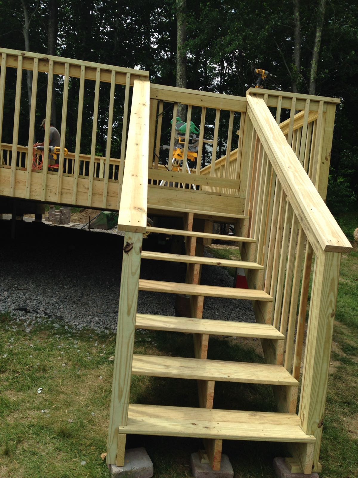 Wood deck stairs leading down to a grassy yard, flanked by railings by Rome Leite Home Improvement in Danbury, CT