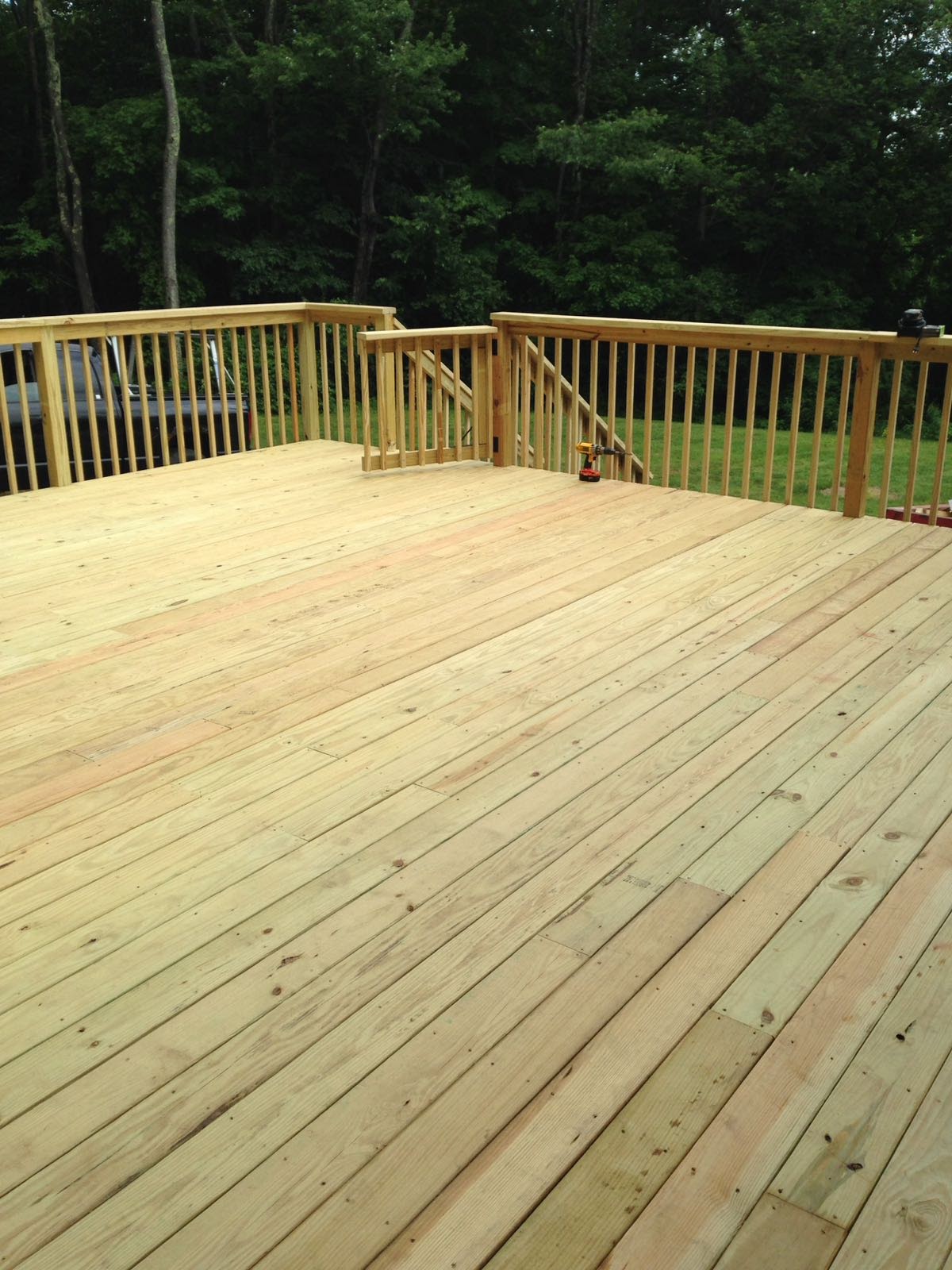 View down a wood deck staircase toward a lawn and driveway by Rome Leite Home Improvement in Danbury, CT