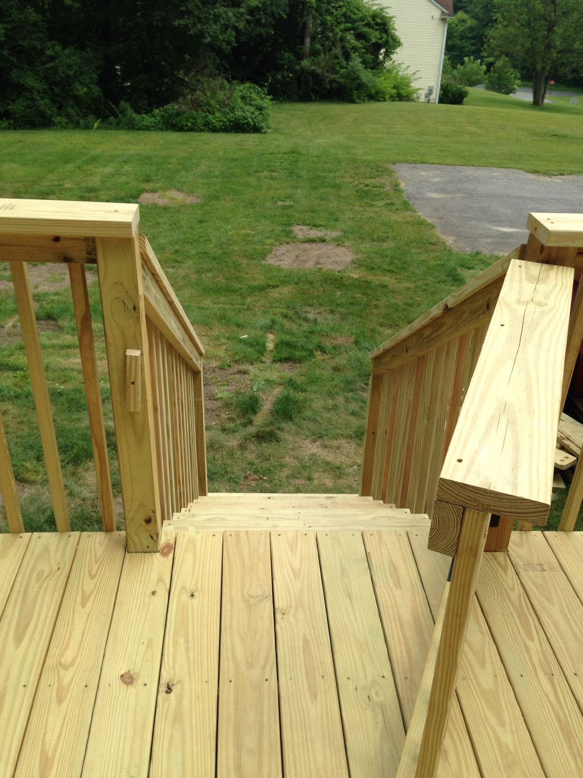 Deck floor joists under construction beside a house, with a white picket fence by Rome Leite Home Improvement in Danbury, CT