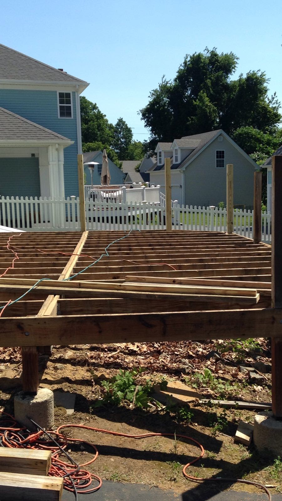 Deck floor joists under construction against a house with a sliding door by Rome Leite Home Improvement in Danbury, CT