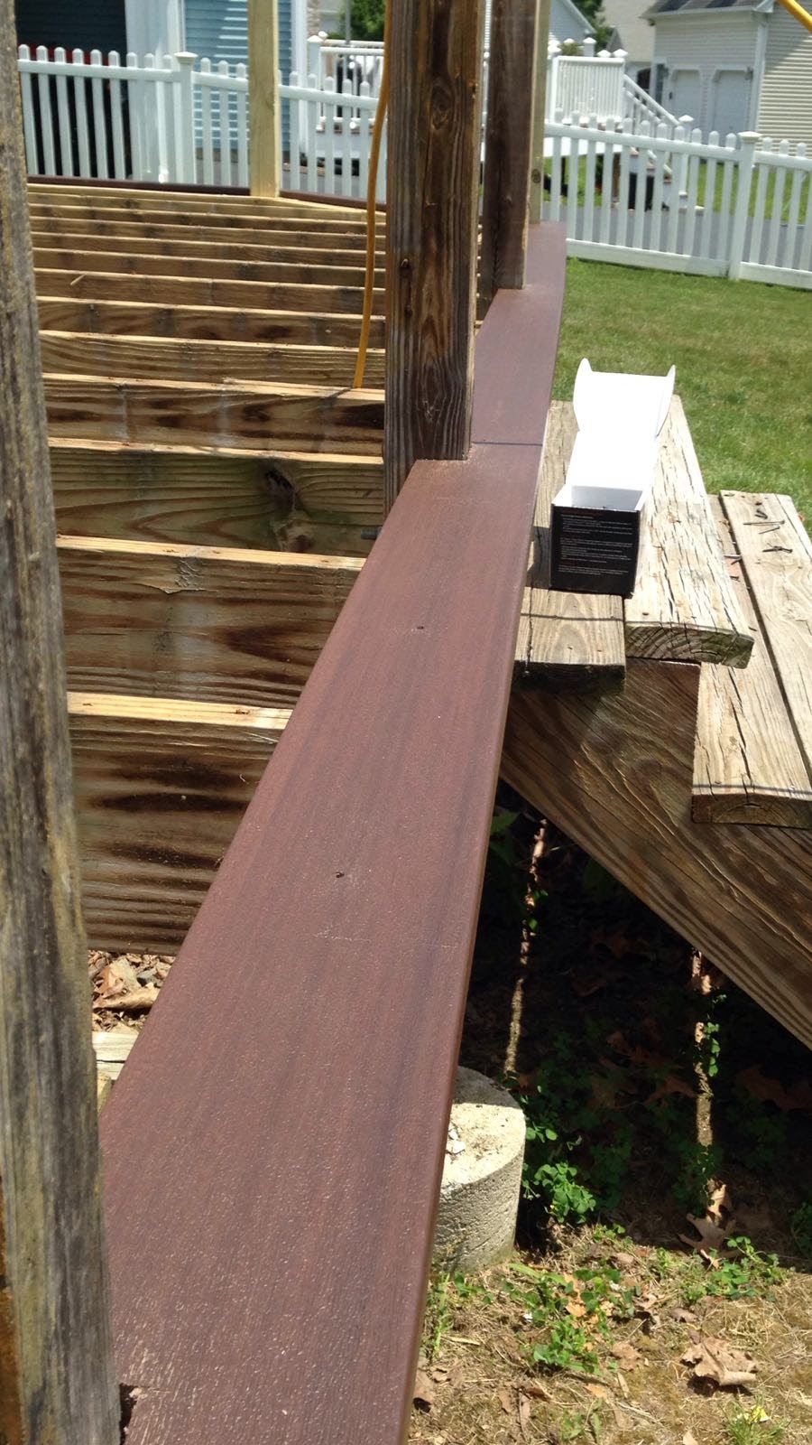 Deck corner post framing next to a house with a picket fence in the background by Rome Leite Home Improvement in Danbury, CT