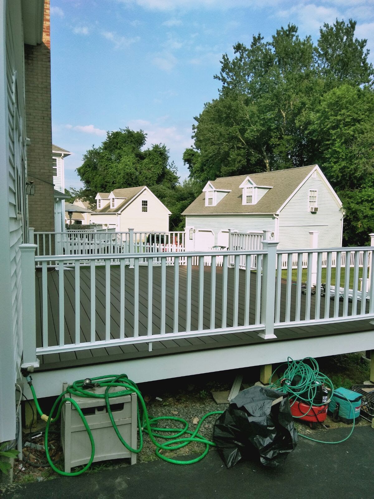 Deck staircase with white railings leading up to a seating area with a patio table by Rome Leite Home Improvement in Danbury, CT