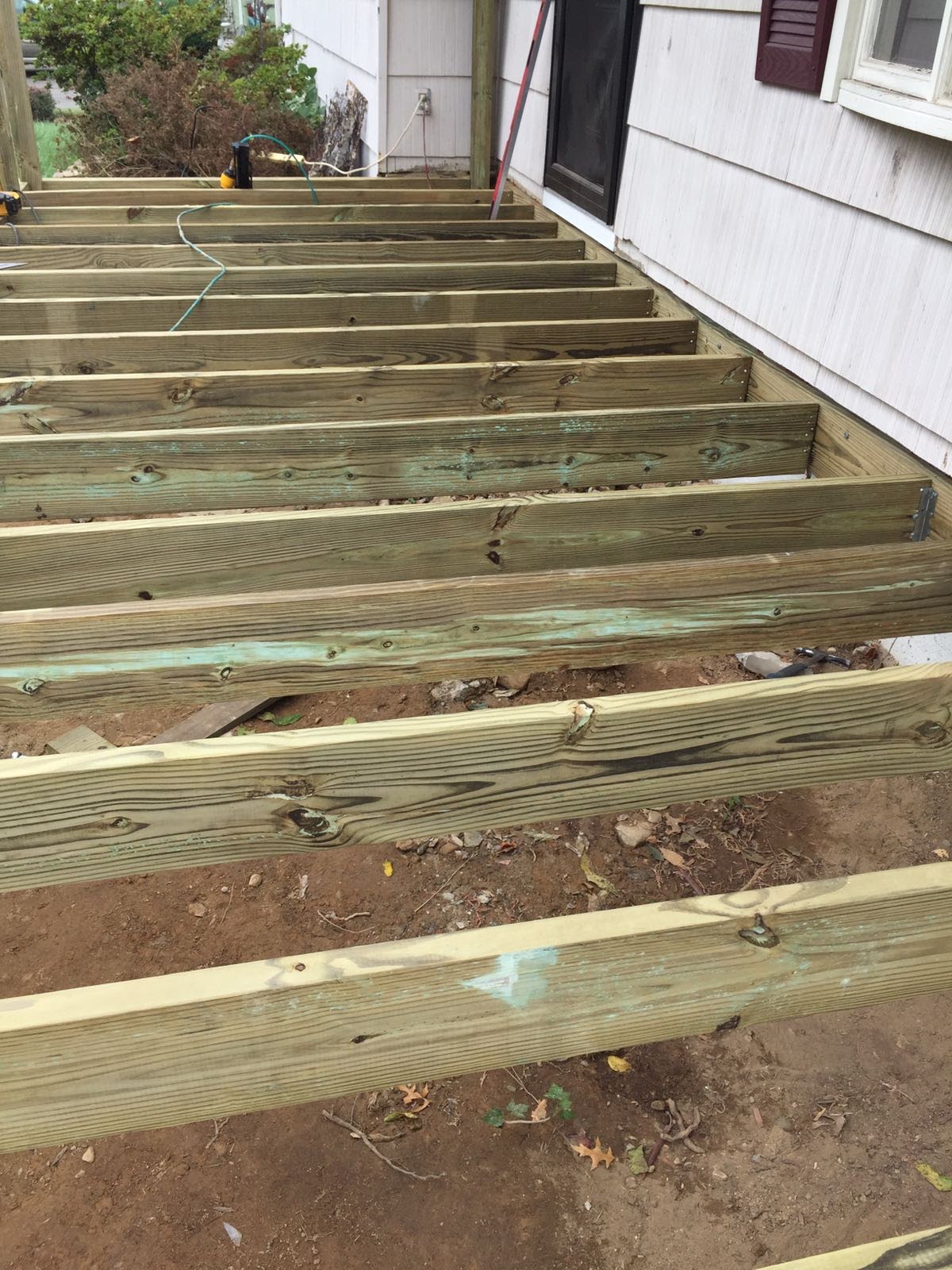 Deck floor joists under construction attached to a house near a front door by Rome Leite Home Improvement in Danbury, CT
