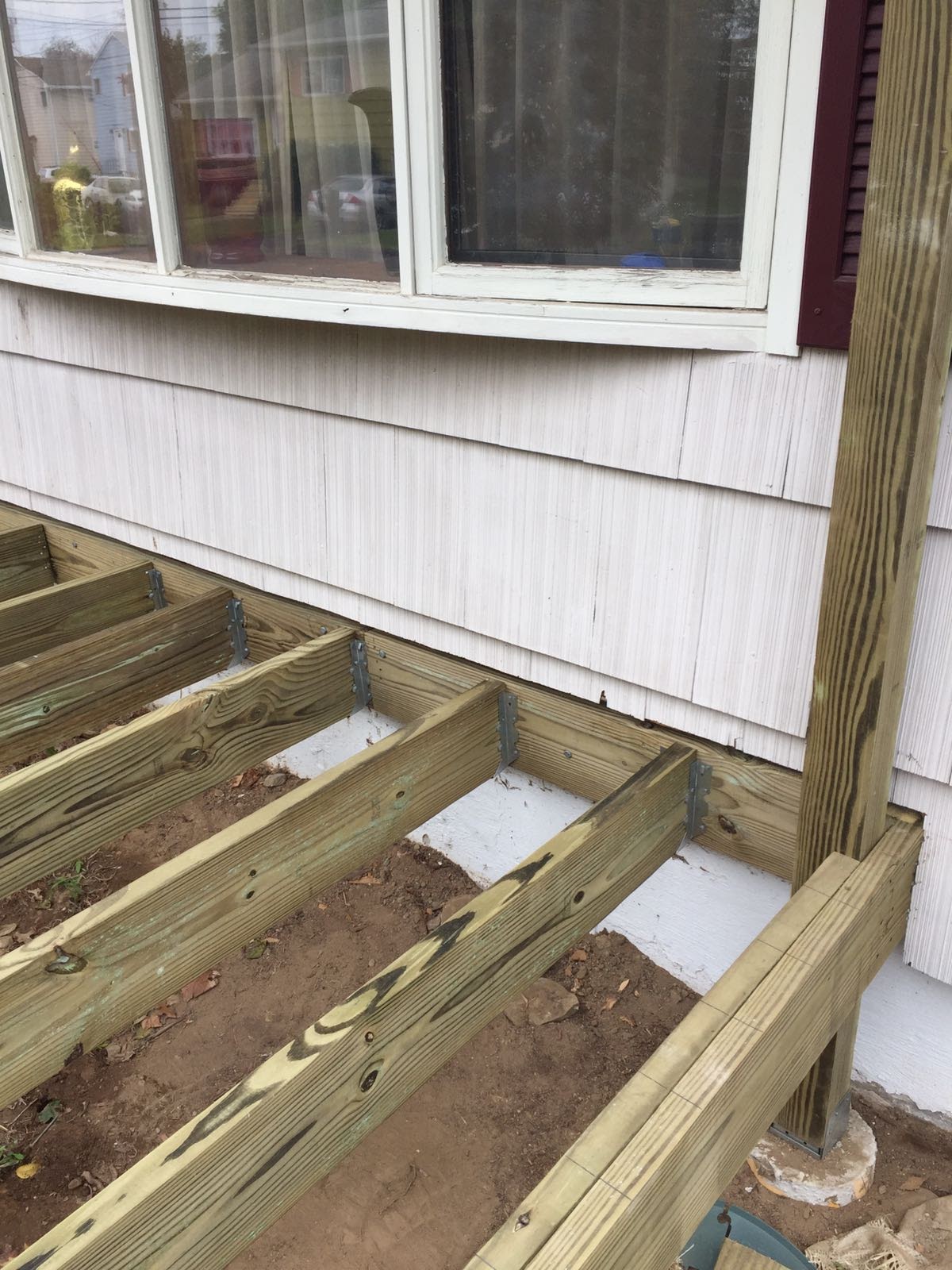 Deck floor joists with metal hangers installed beneath a bay window by Rome Leite Home Improvement in Danbury, CT
