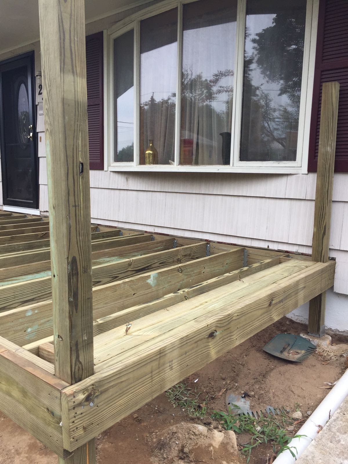 Front porch deck framing with two support posts flanking a window by Rome Leite Home Improvement in Danbury, CT
