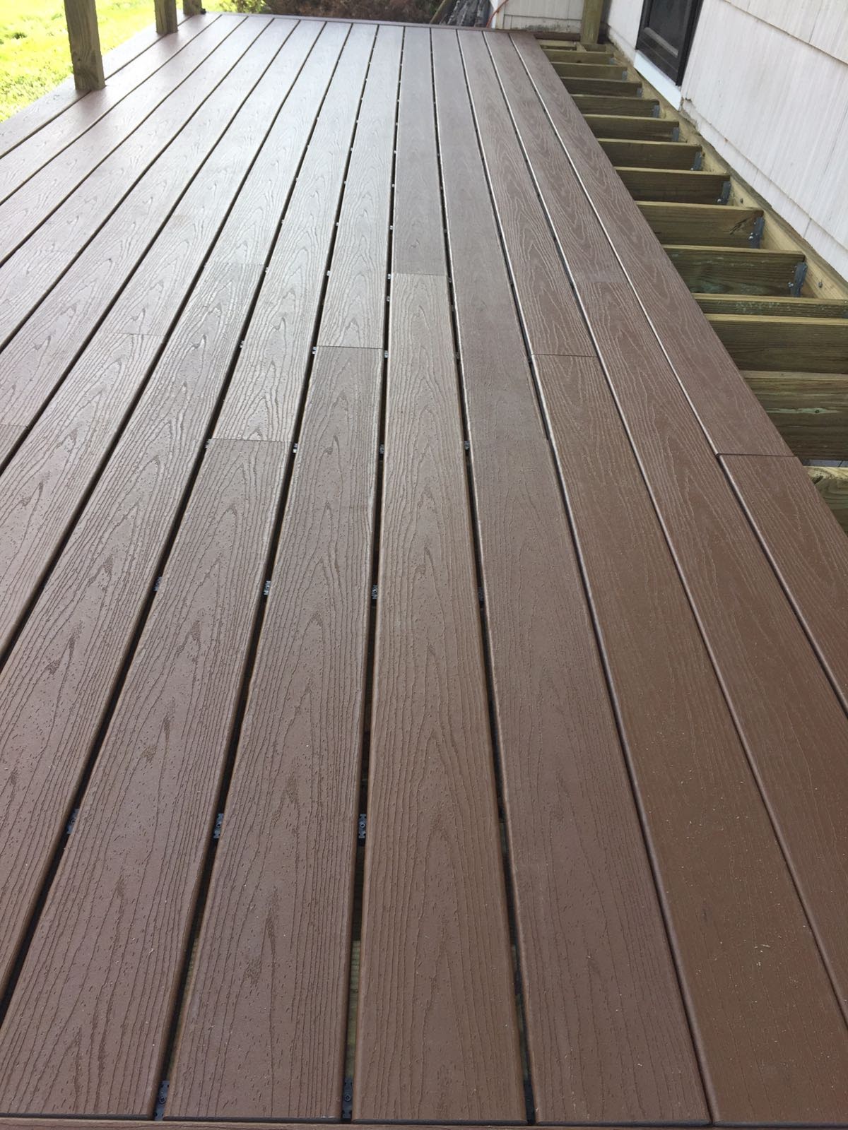 Close-up of newly installed composite deck boards leading toward a house by Rome Leite Home Improvement in Danbury, CT