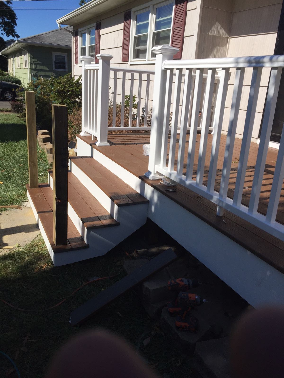 Composite deck steps and white vinyl railing under construction with tools on the treads by Rome Leite Home Improvement in Danbury, CT