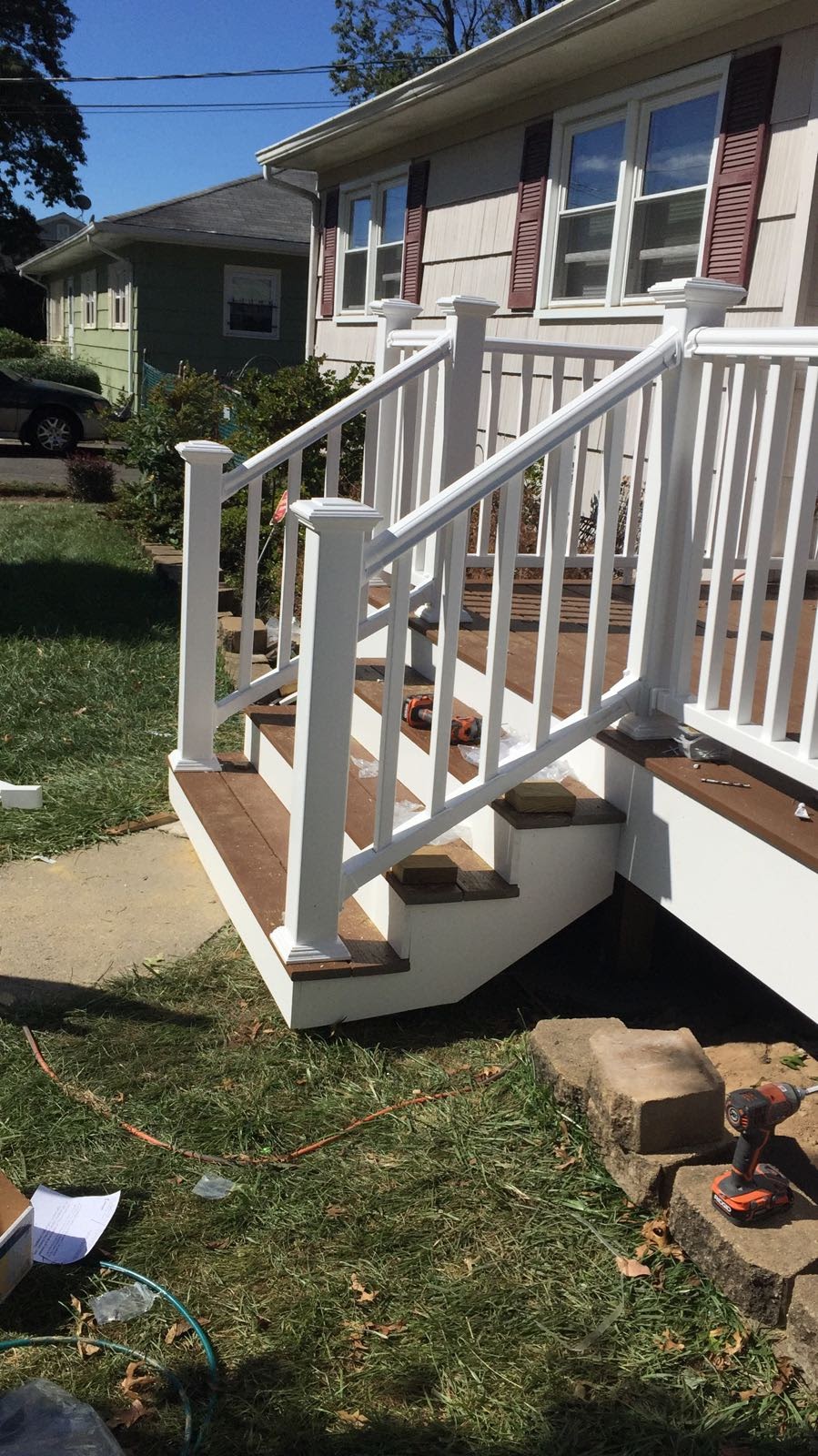 White vinyl deck railing and steps being assembled, with tools and hardware on the deck boards by Rome Leite Home Improvement in Danbury, CT