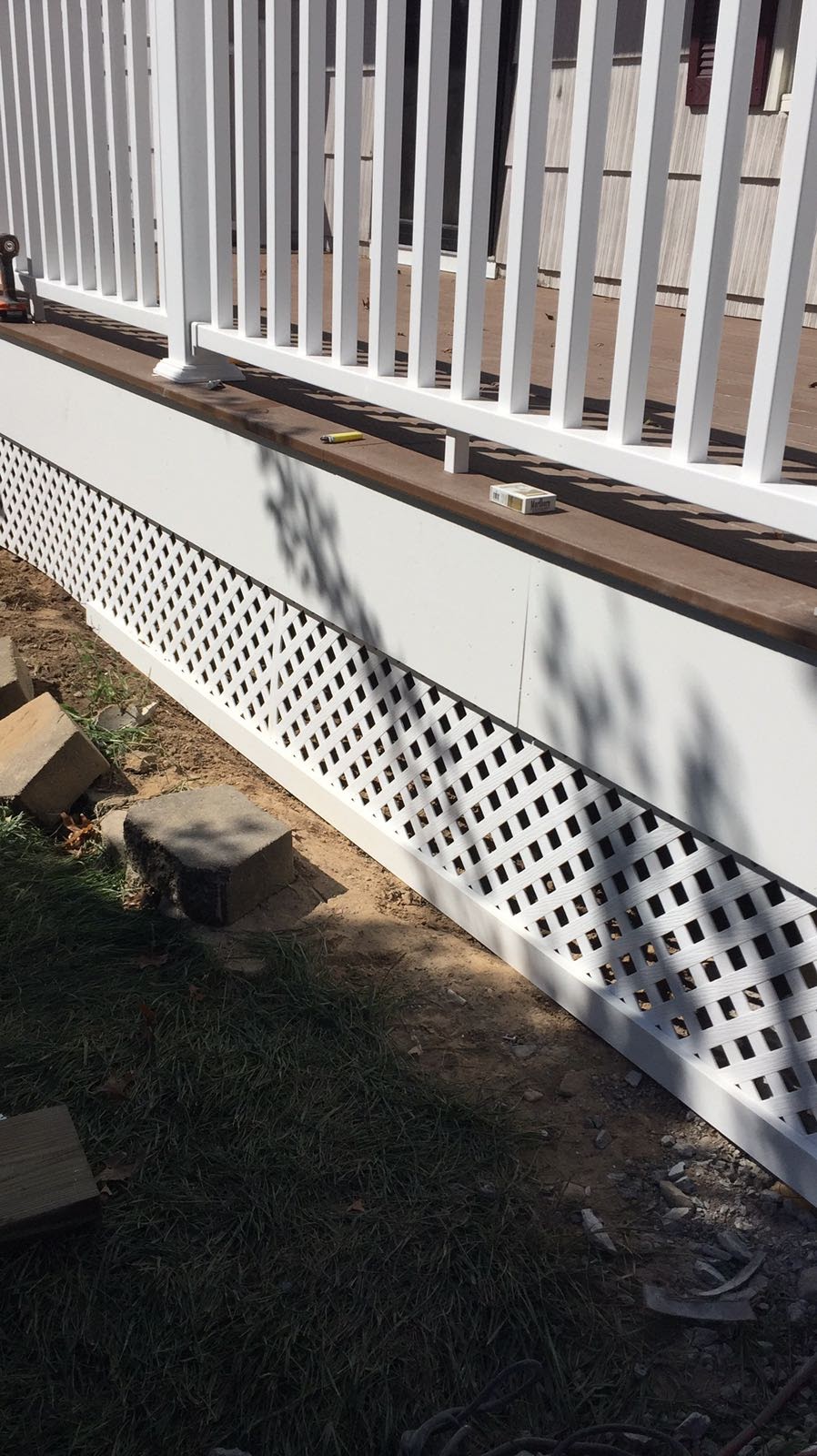 Finished front deck with white vinyl railing and steps, with construction debris in the yard by Rome Leite Home Improvement in Danbury, CT