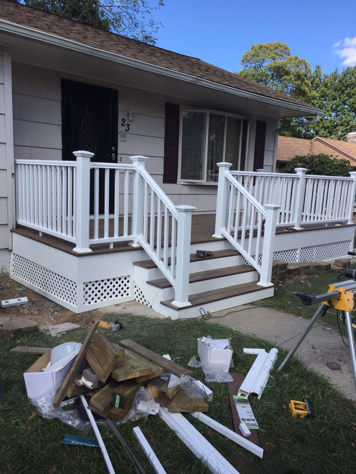 Finished front porch deck with white vinyl railings and composite steps leading to the front door by Rome Leite Home Improvement in Danbury, CT
