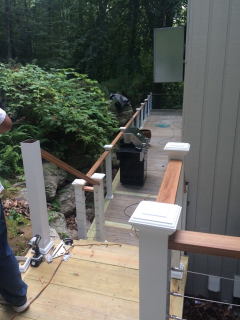 Wood deck and stairs descending a hillside, with cable railing by Rome Leite Home Improvement in Danbury, CT
