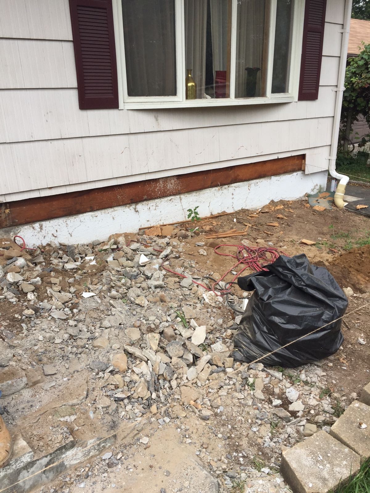 Pile of demolition debris beside a house foundation with old wood trim removed by Rome Leite Home Improvement in Danbury, CT