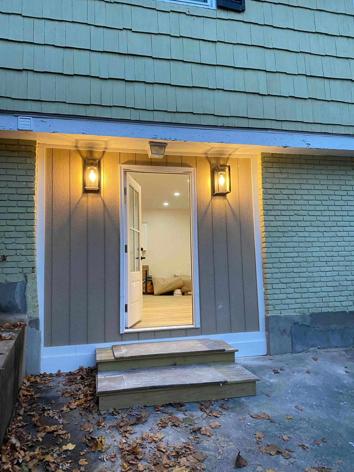 Evening exterior shot of a new entry door and wood steps on an addition by Rome Leite Home Improvement in Danbury, CT