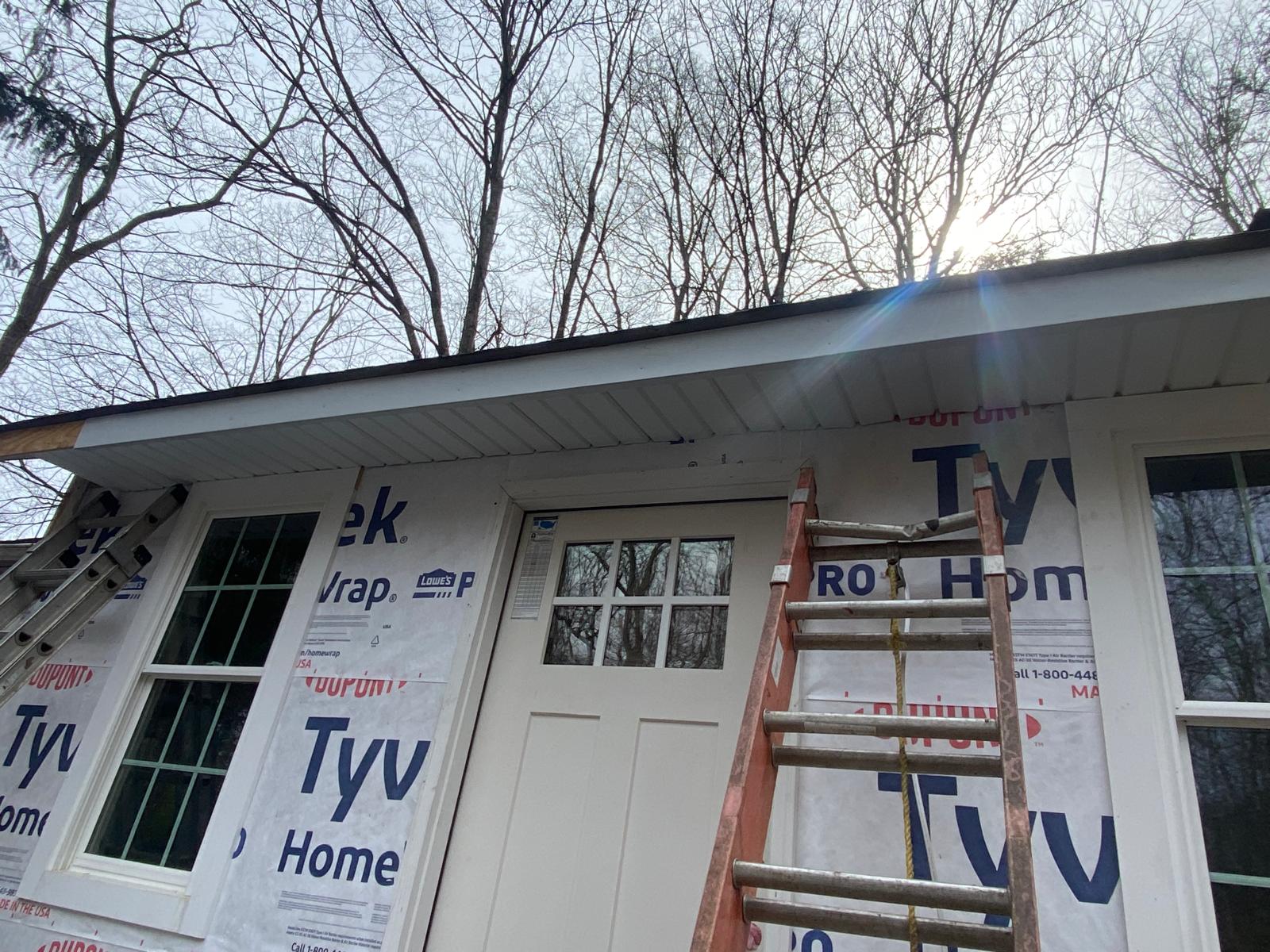 Exterior of a house addition mid-construction with house wrap and a newly installed door and window by Rome Leite Home Improvement in Danbury, CT