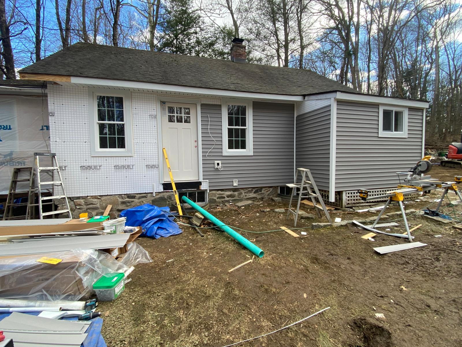Exterior of a house with newly installed gray siding and a white door by Rome Leite Home Improvement in Danbury, CT