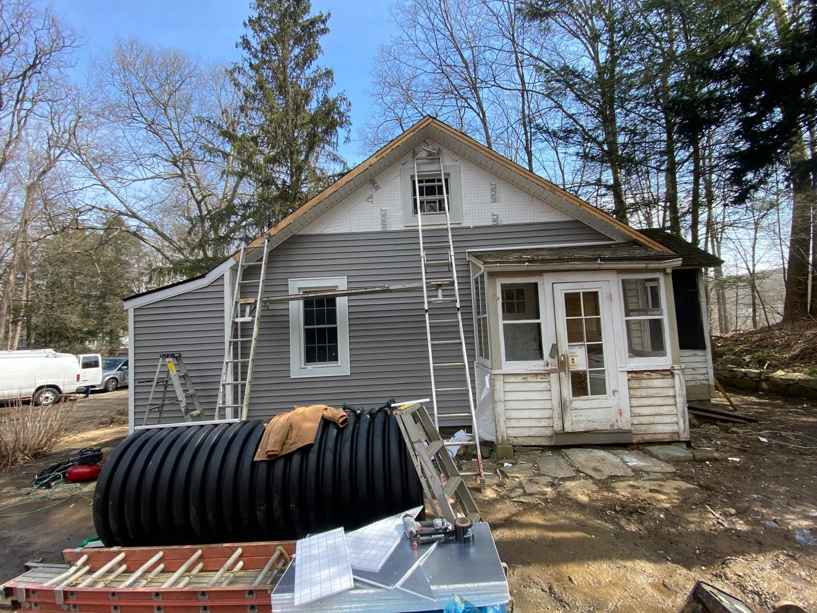 Exterior of an older house with peeling painted wood siding and a plywood-boarded section by Rome Leite Home Improvement in Danbury, CT