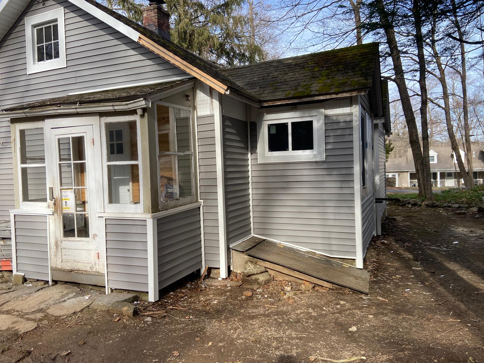 Exterior of a gray-sided house with an older enclosed porch and a wood ramp by Rome Leite Home Improvement in Danbury, CT