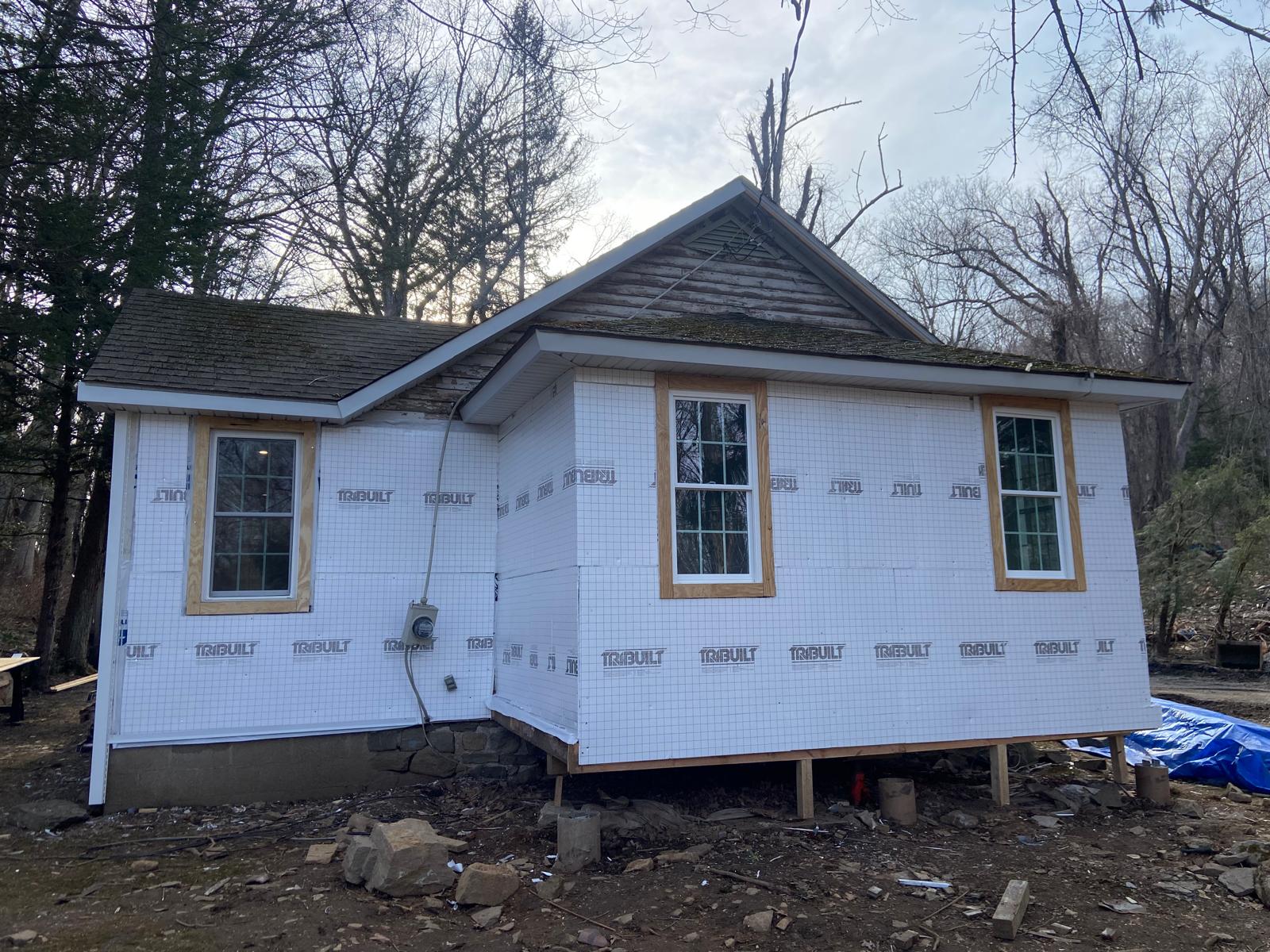 Exterior of a house under construction with house wrap and newly trimmed windows, at dusk by Rome Leite Home Improvement in Danbury, CT