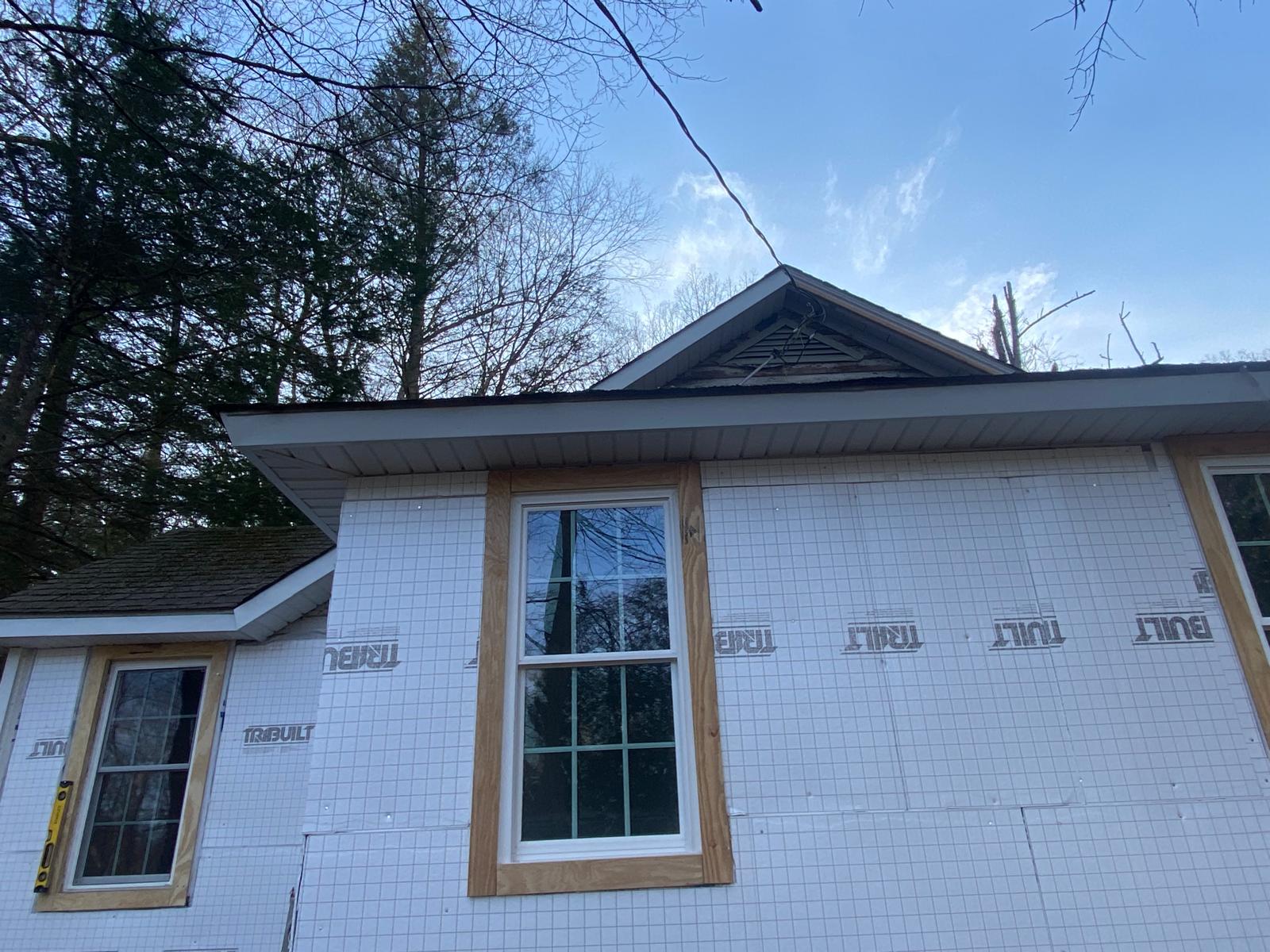 Close-up looking up at a gable roof peak and eave with house wrap and a newly trimmed window by Rome Leite Home Improvement in Danbury, CT