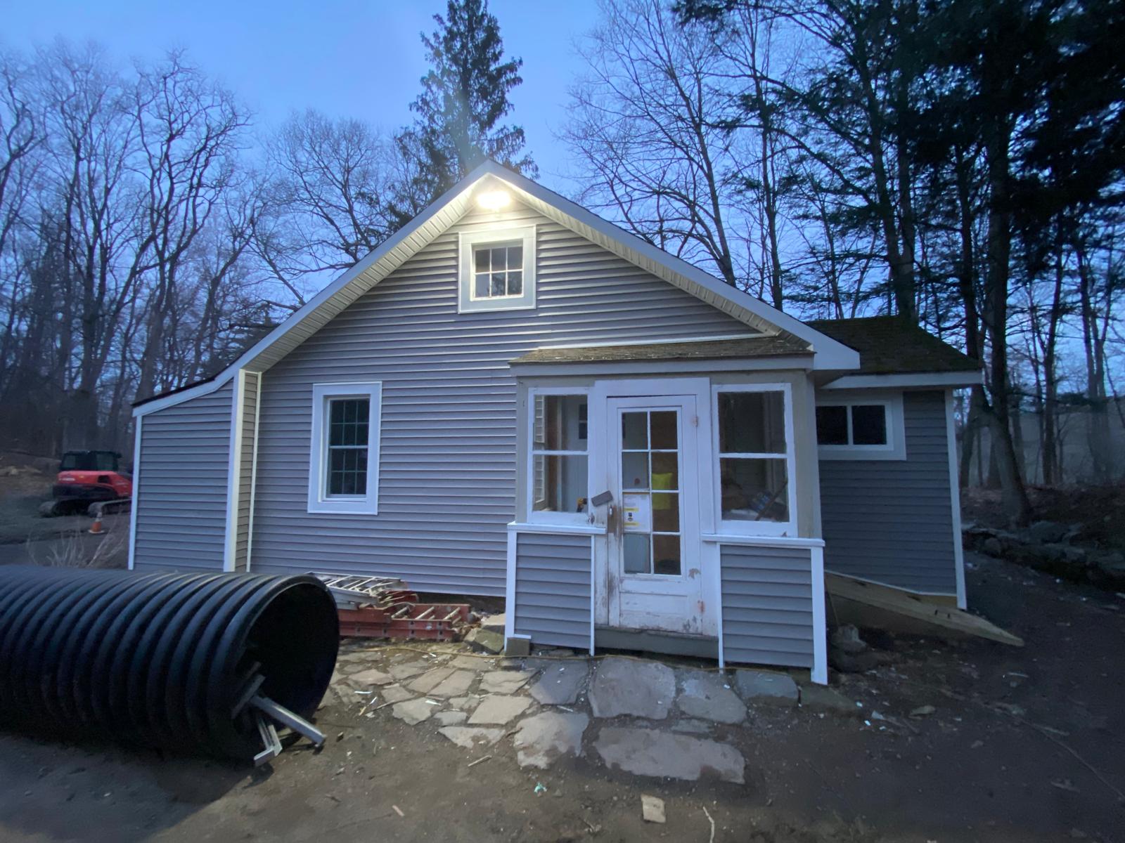 Exterior of a finished gray-sided house at dusk with a porch by Rome Leite Home Improvement in Danbury, CT