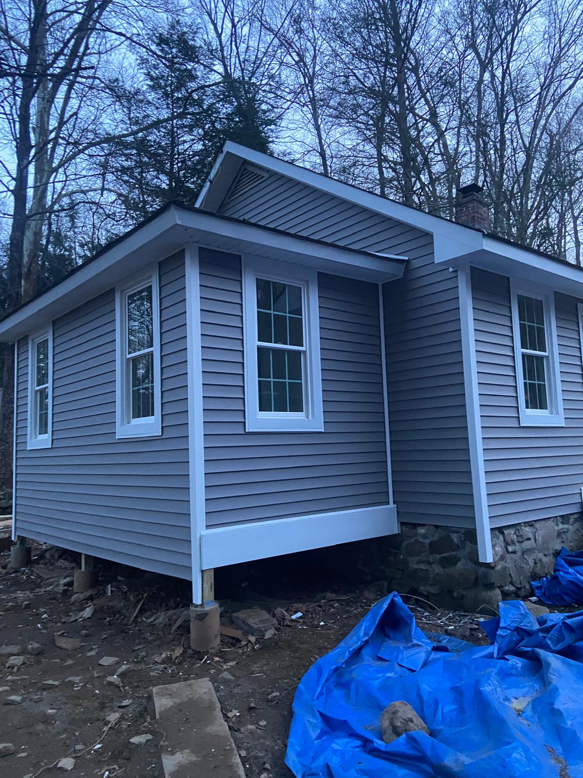 Corner exterior view of a finished gray-sided house with multiple windows, evening light by Rome Leite Home Improvement in Danbury, CT
