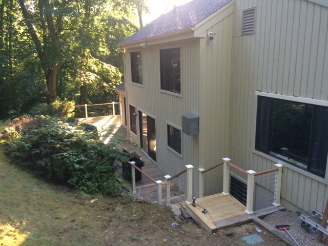 Wide exterior view of a gray two-story house with a deck and cable railing by Rome Leite Home Improvement in Danbury, CT
