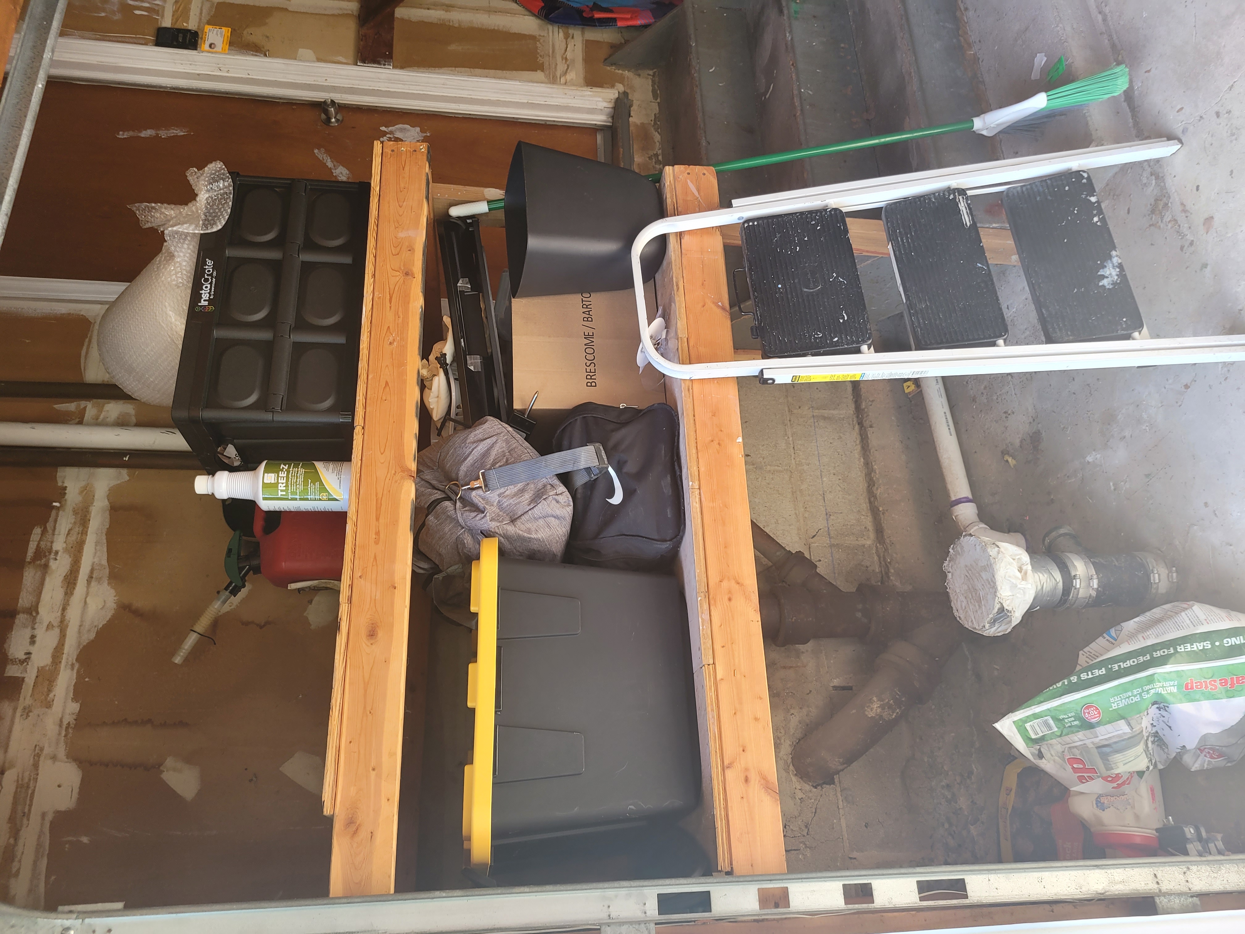 Garage storage area with a stepladder, storage bins, and a wood door by Rome Leite Home Improvement in Danbury, CT