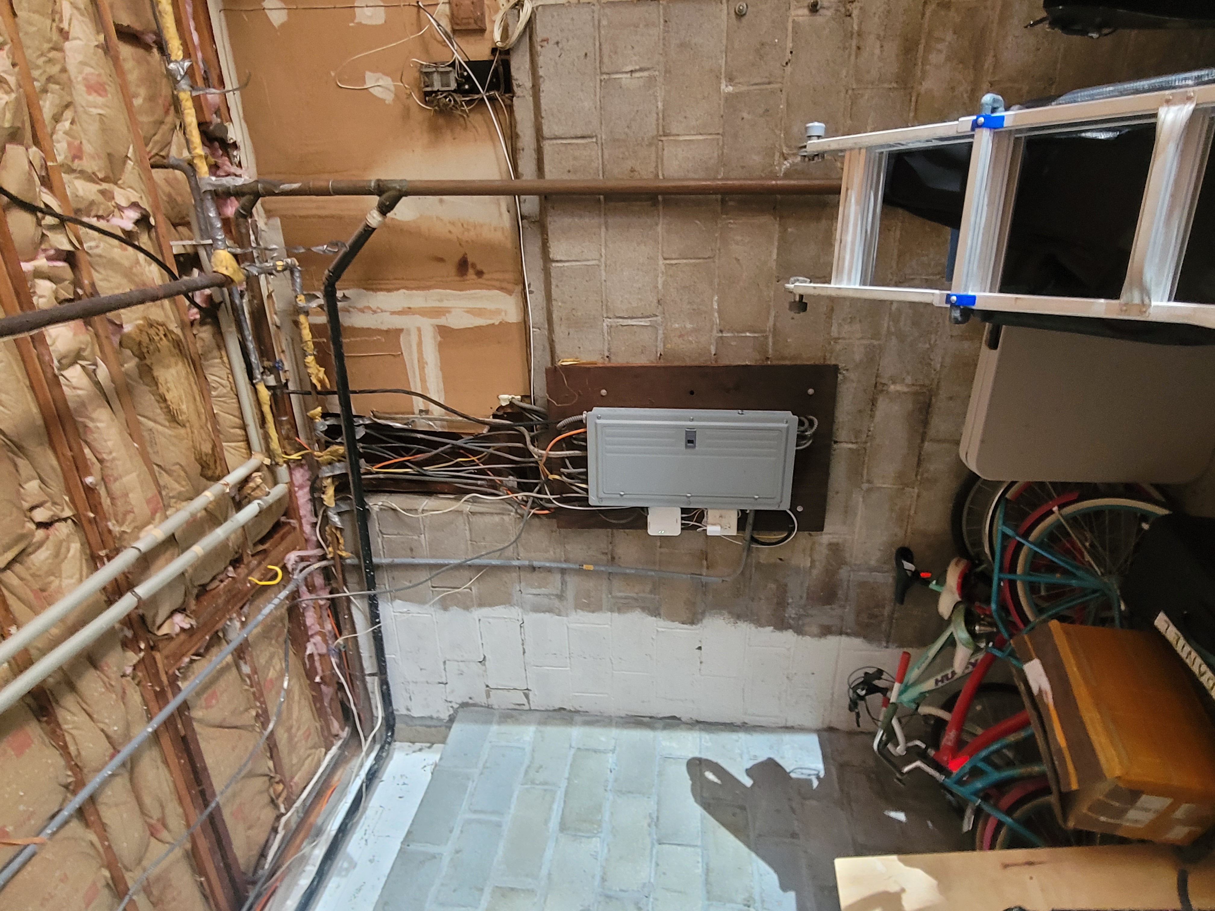 New electrical panel mounted on an unfinished garage wall with exposed insulation by Rome Leite Home Improvement in Danbury, CT