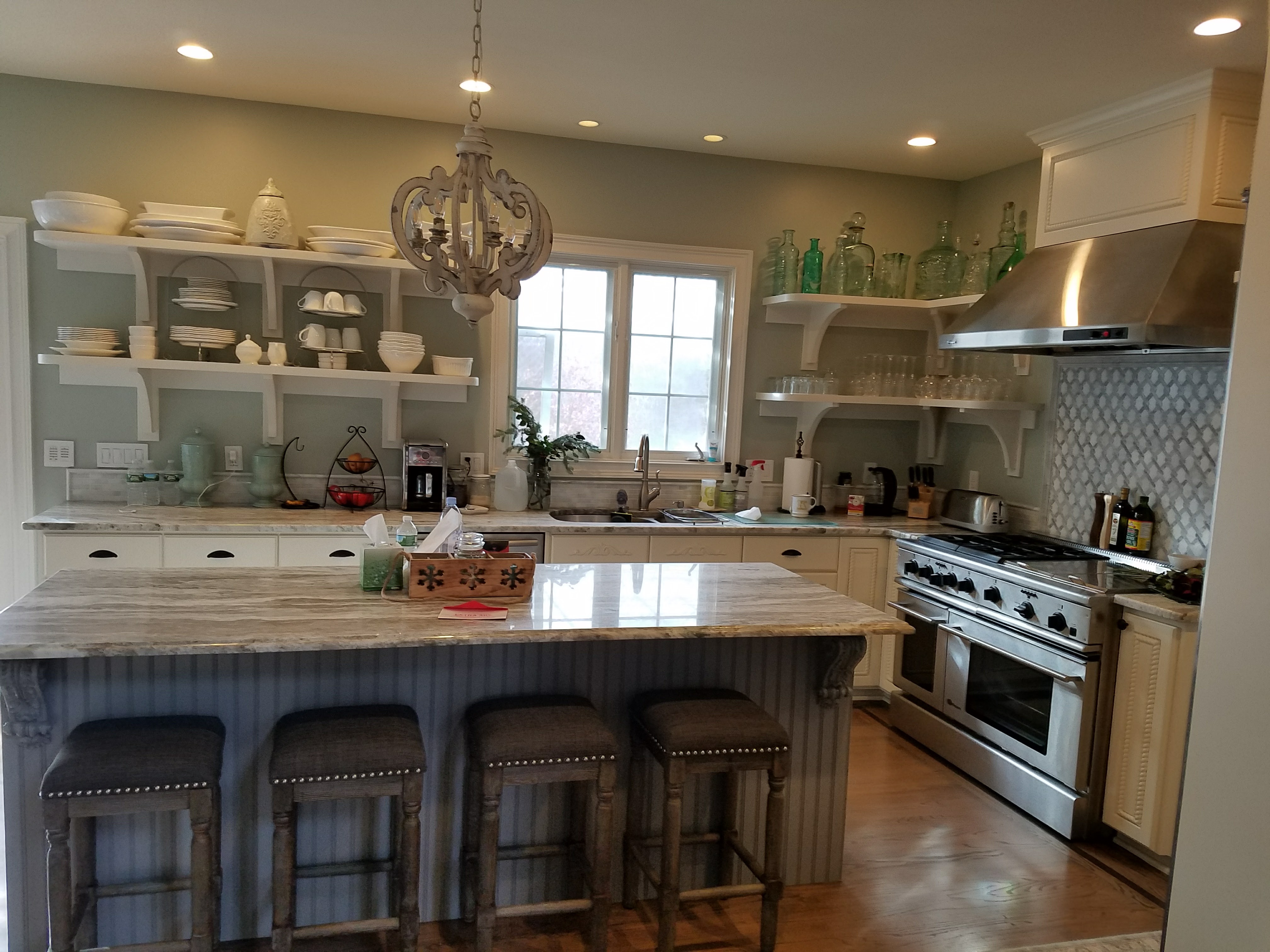 Finished kitchen viewed from the breakfast bar with upholstered stools, open shelving, and a professional range by Rome Leite Home Improvement in Danbury, CT