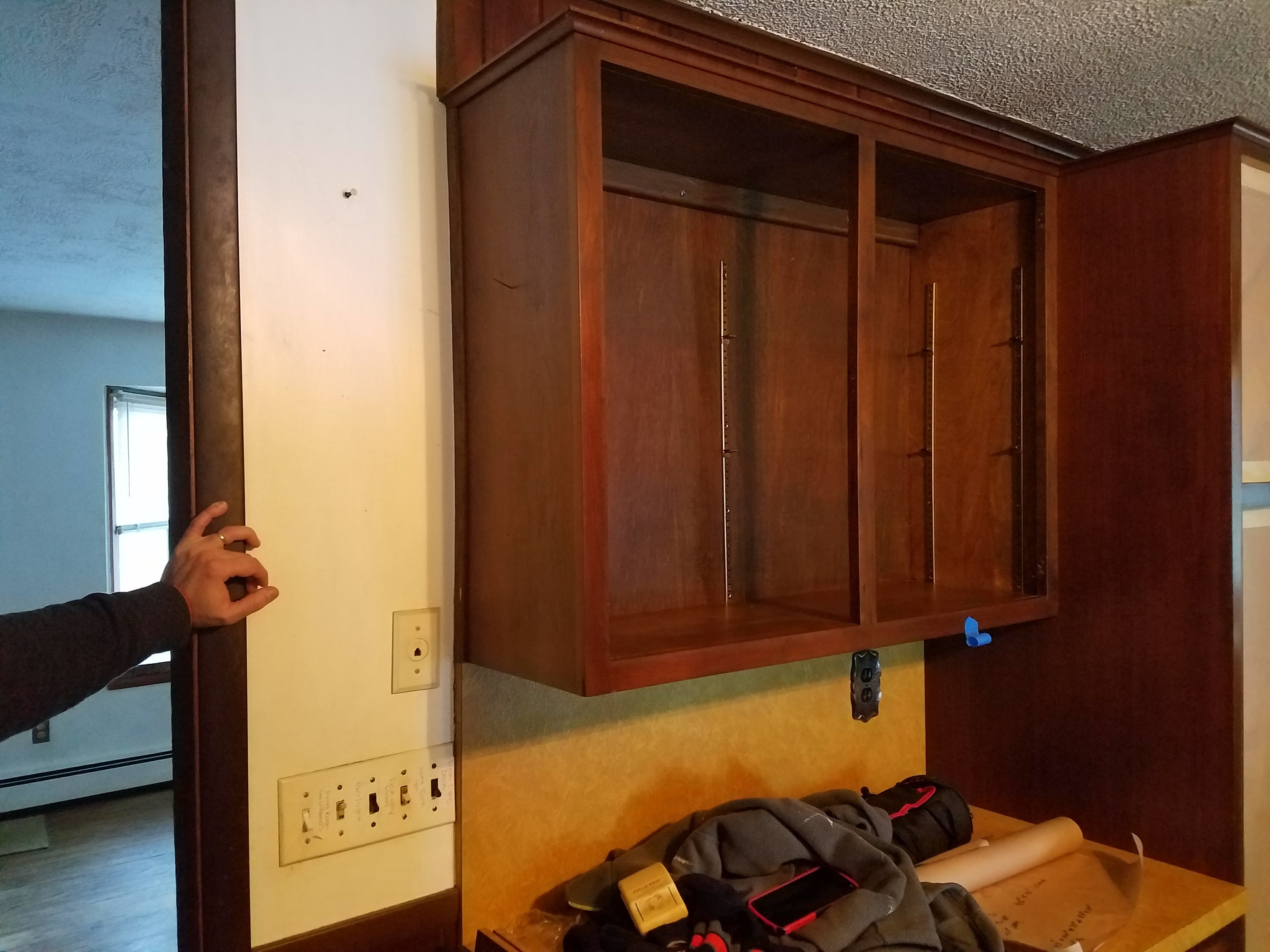 Upper wood kitchen cabinet being installed with adjustable shelf pin strips visible by Rome Leite Home Improvement in Danbury, CT